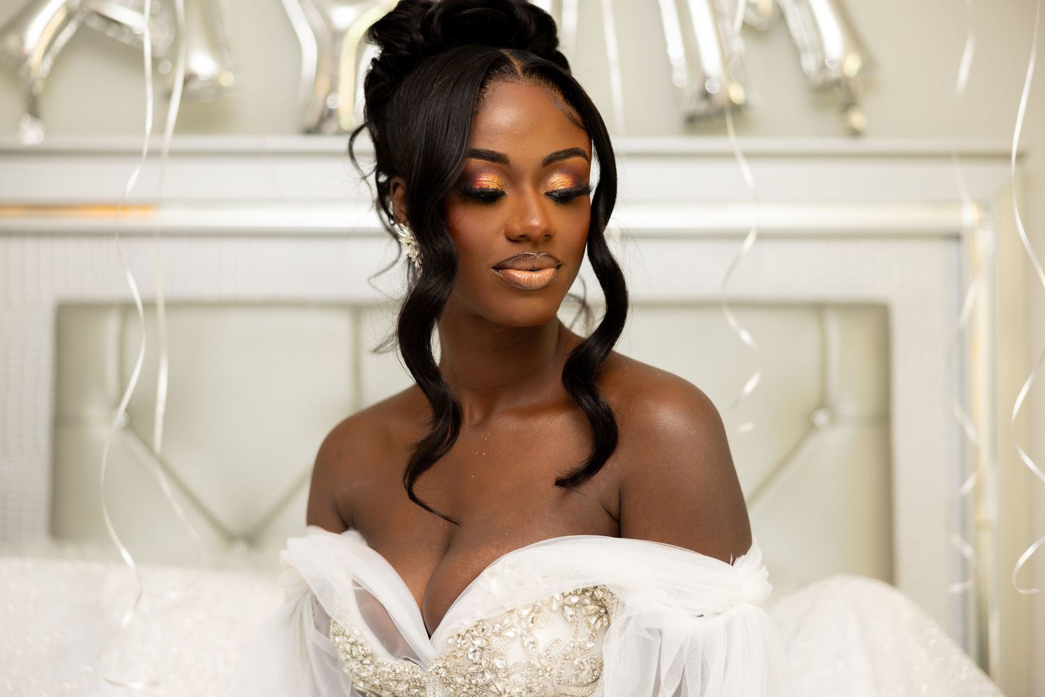 Elegant bridal portrait featuring an off-shoulder white wedding gown against a light background.