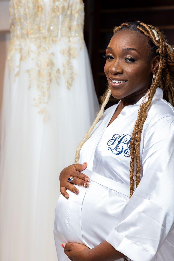 Elegant white bridal robe with monogram displayed next to wedding dress.