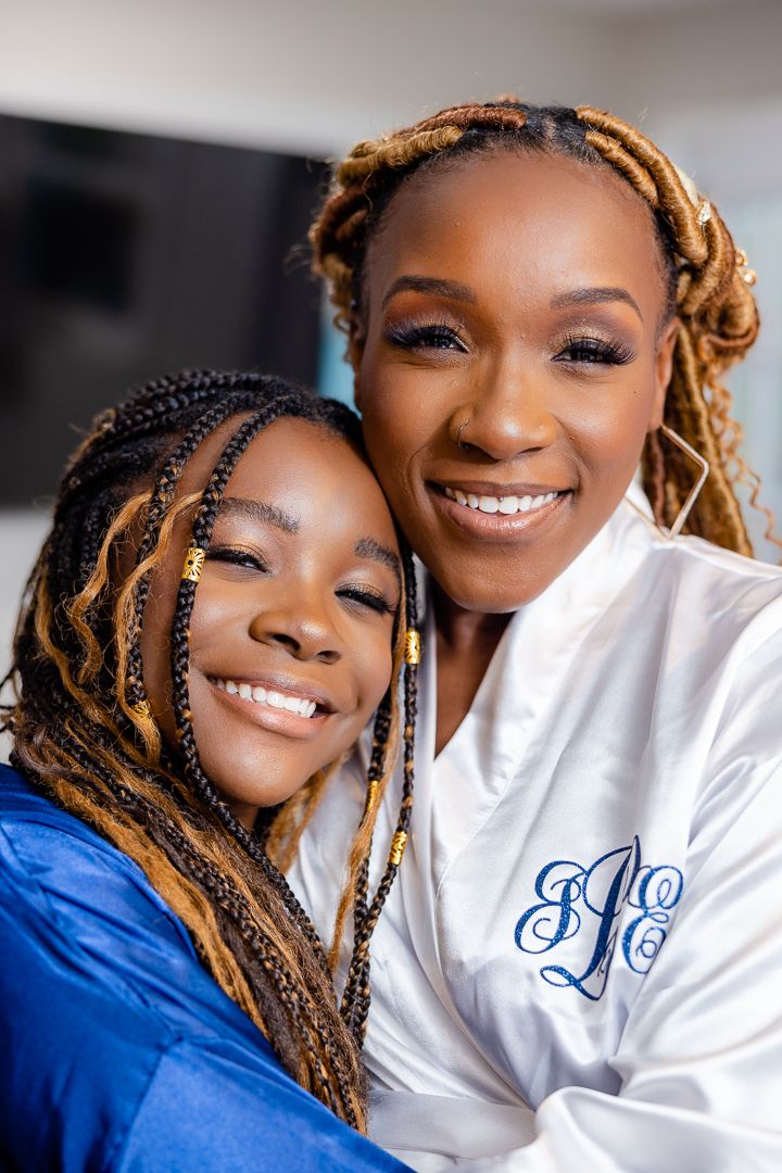 Two people in white monogrammed robes sharing a close embrace and smiling.