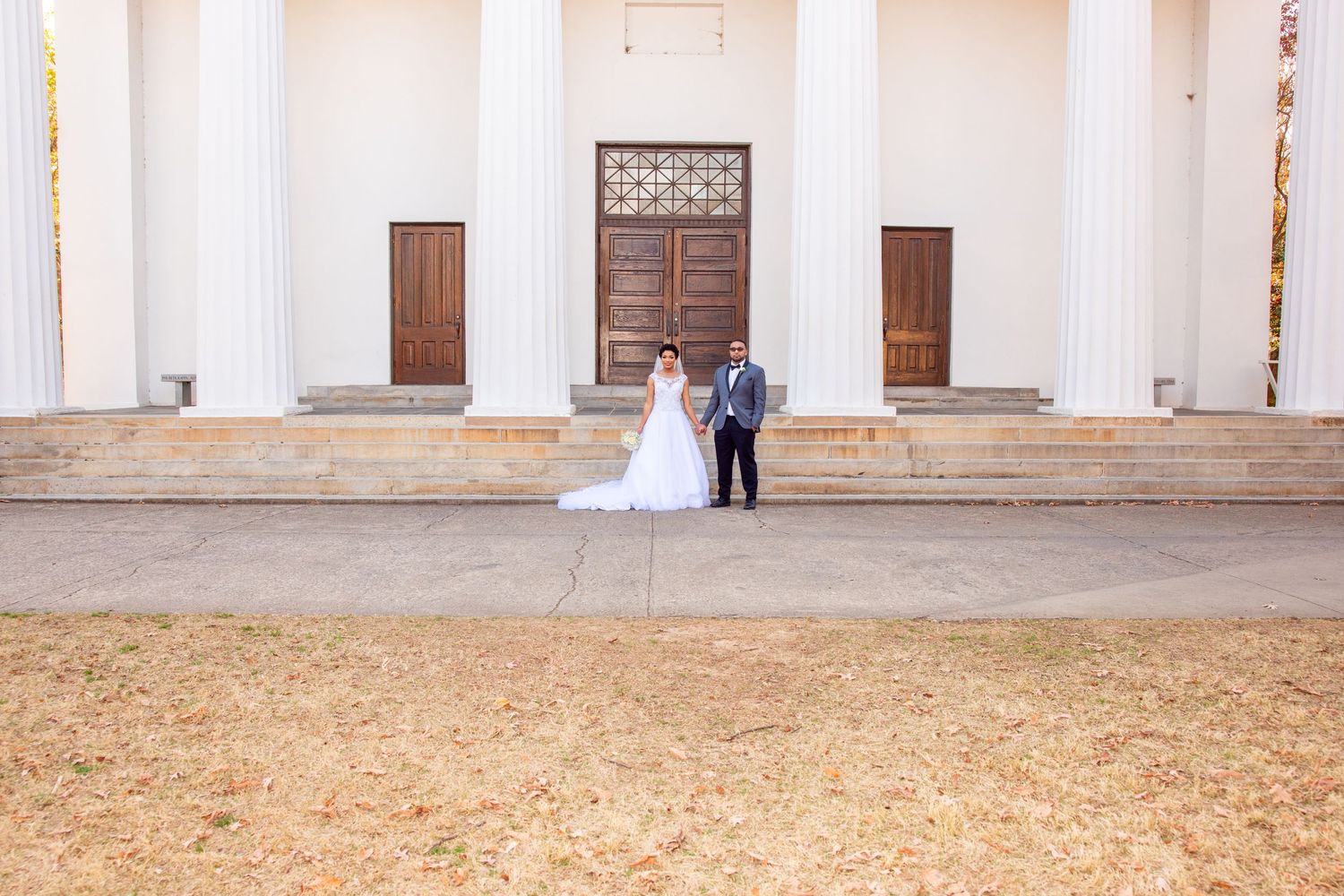 Elegant white columned building serves as backdrop for outdoor wedding venue.