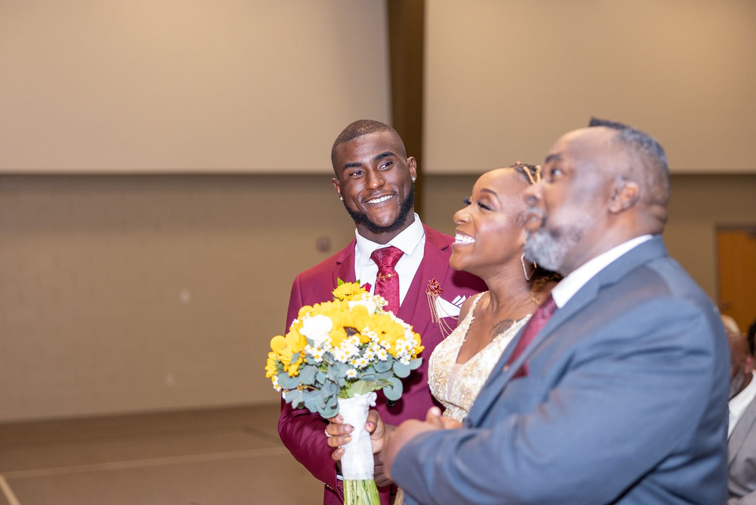 Formal wedding celebration with guests in burgundy and grey attire.