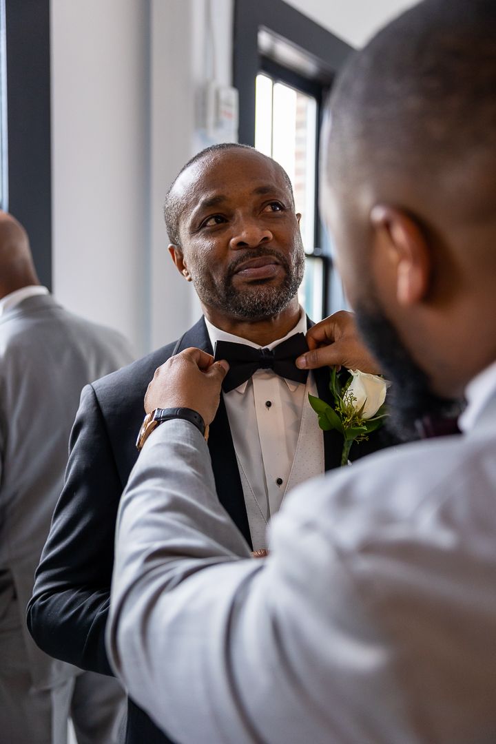 A close-up shows the final adjustments being made to a formal white boutonniere.