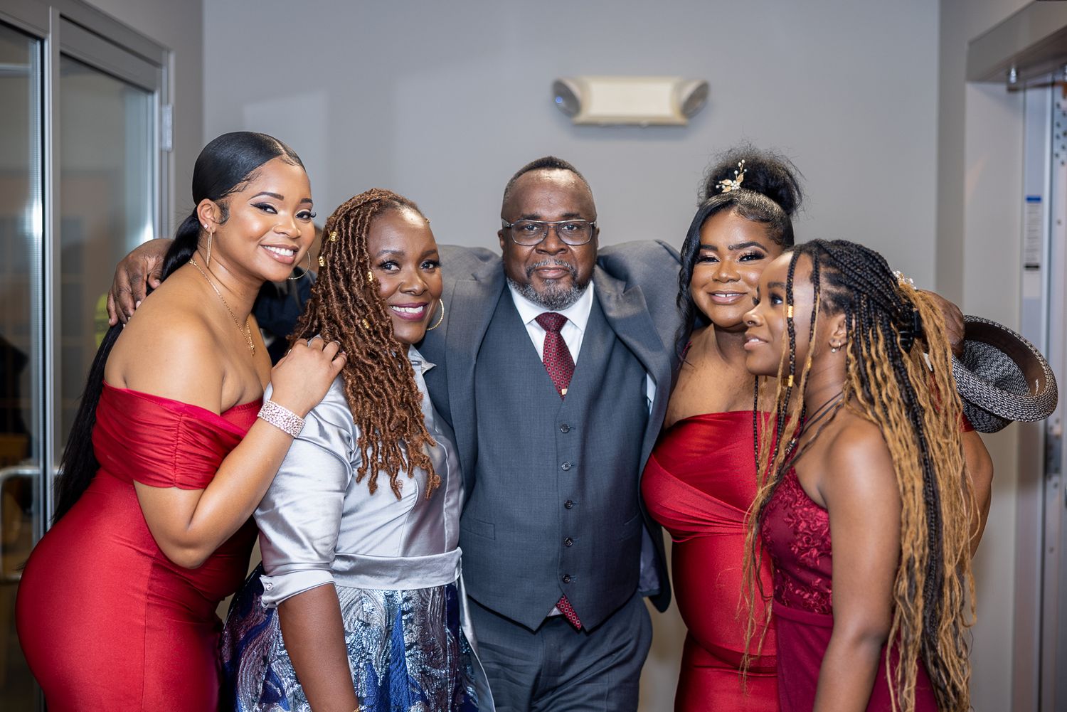 Group photo of people wearing formal attire including red dresses and suits at an elegant event.