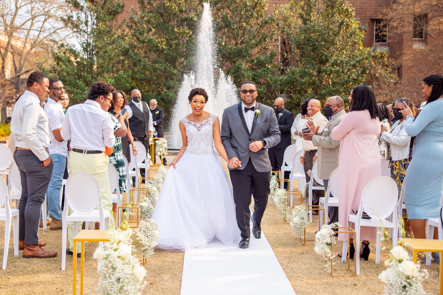Garden wedding ceremony with guests in pastel attire seated on white chairs.