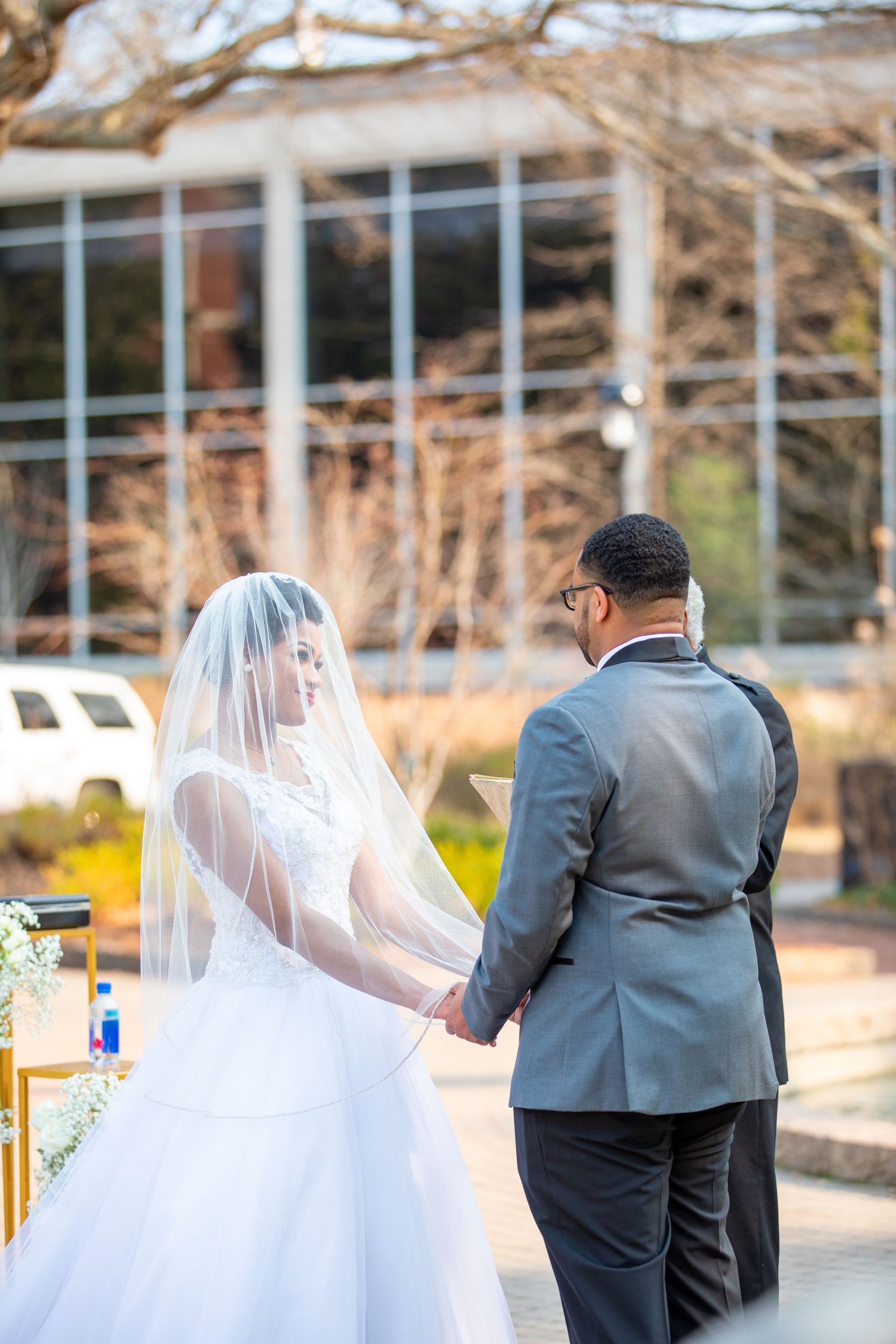 A couple shares a tender moment holding hands during their outdoor wedding ceremony.