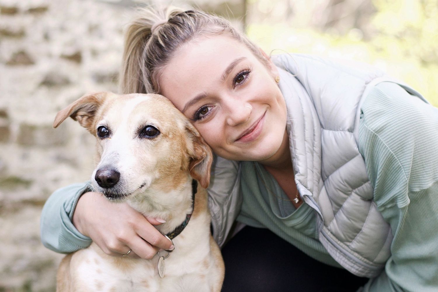 A tan and white dog enjoying outdoor time with her owner in beautiful natural lighting