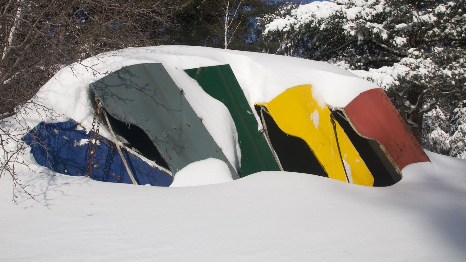 Colorful canoes buried in deep snow during winter.
