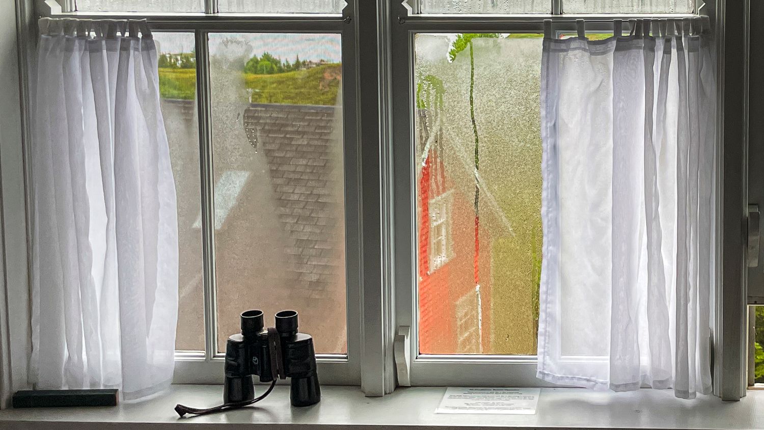 Rows of white curtains hang in front of windows in a modern minimalist interior space.