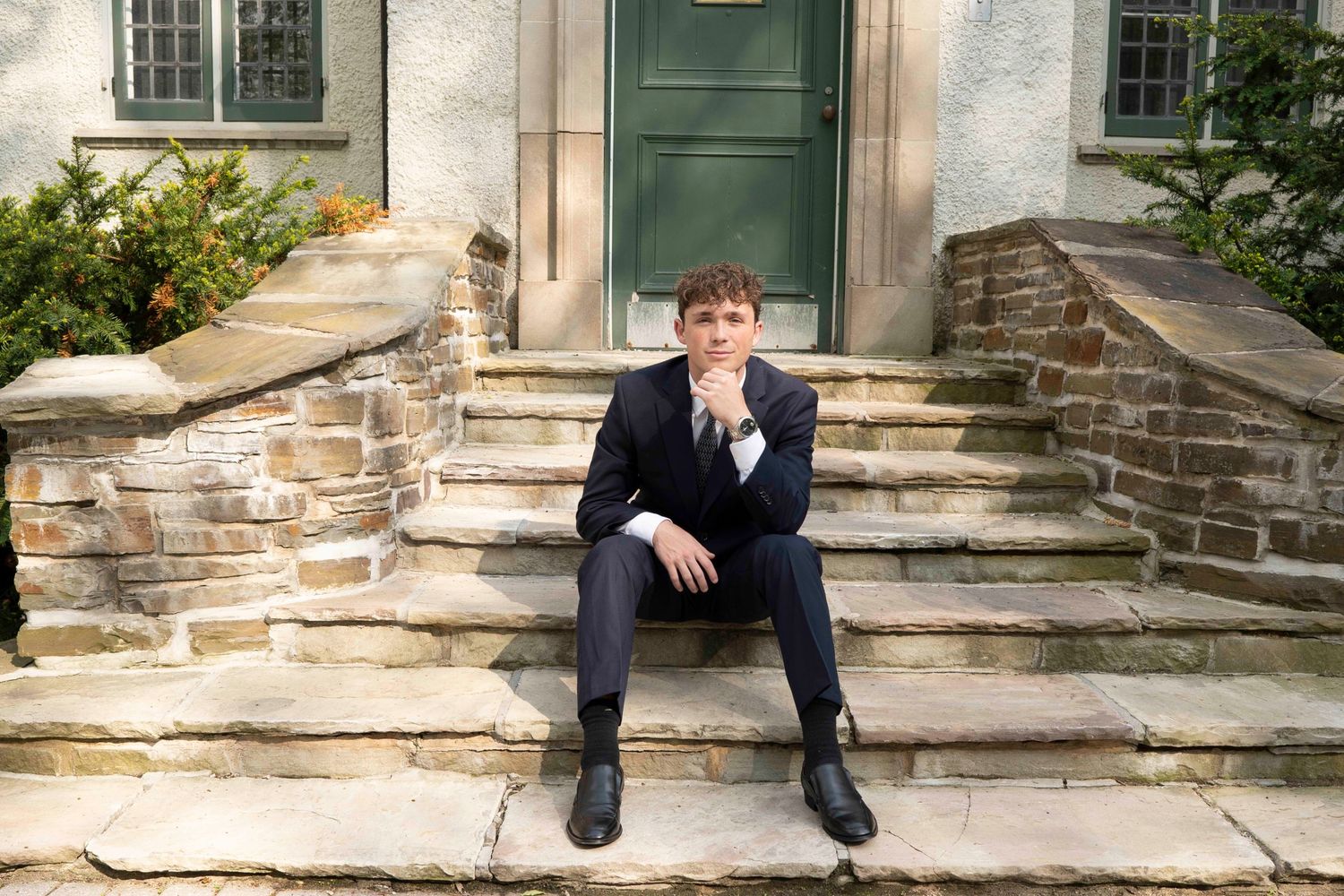 A sequence of five photos showing someone sitting on stone steps in front of a green door and stone building.