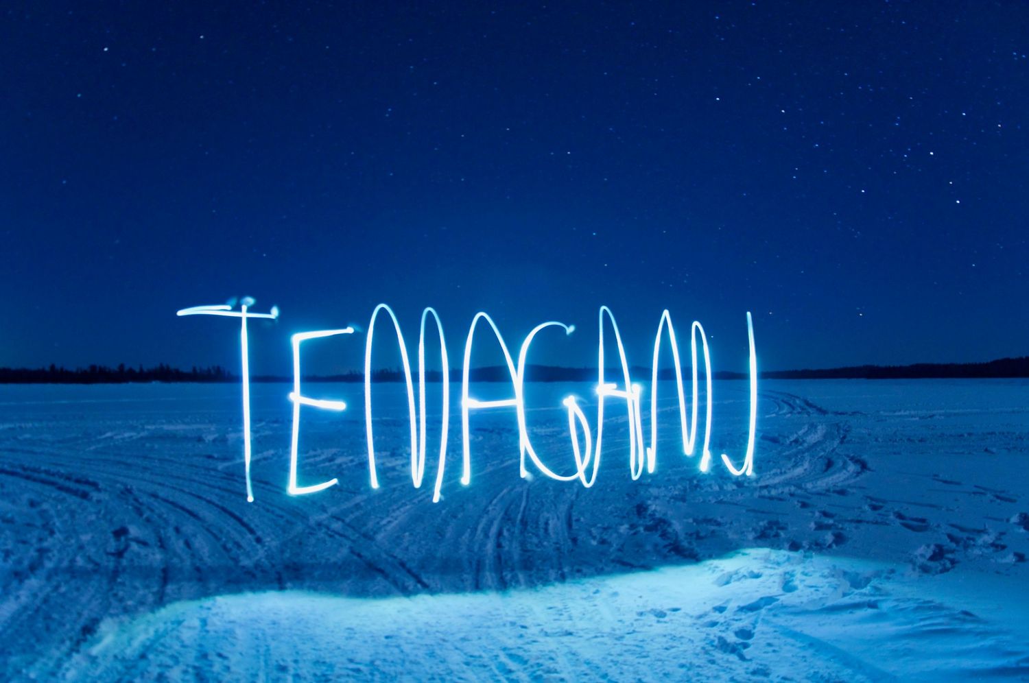 Neon blue text reading 'TENSION' glows against a dark night sky over a snowy mountain landscape.