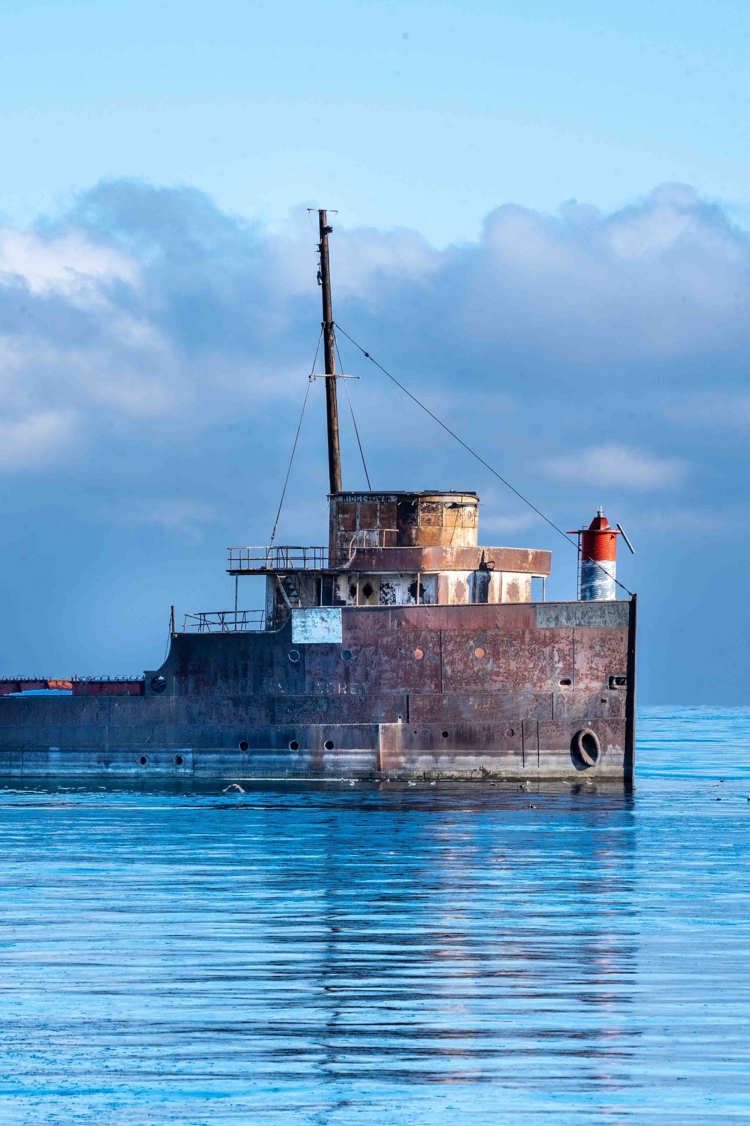 An old laker acts as a breakwater with dramatic clouds, and an icy blue Lake Ontario.