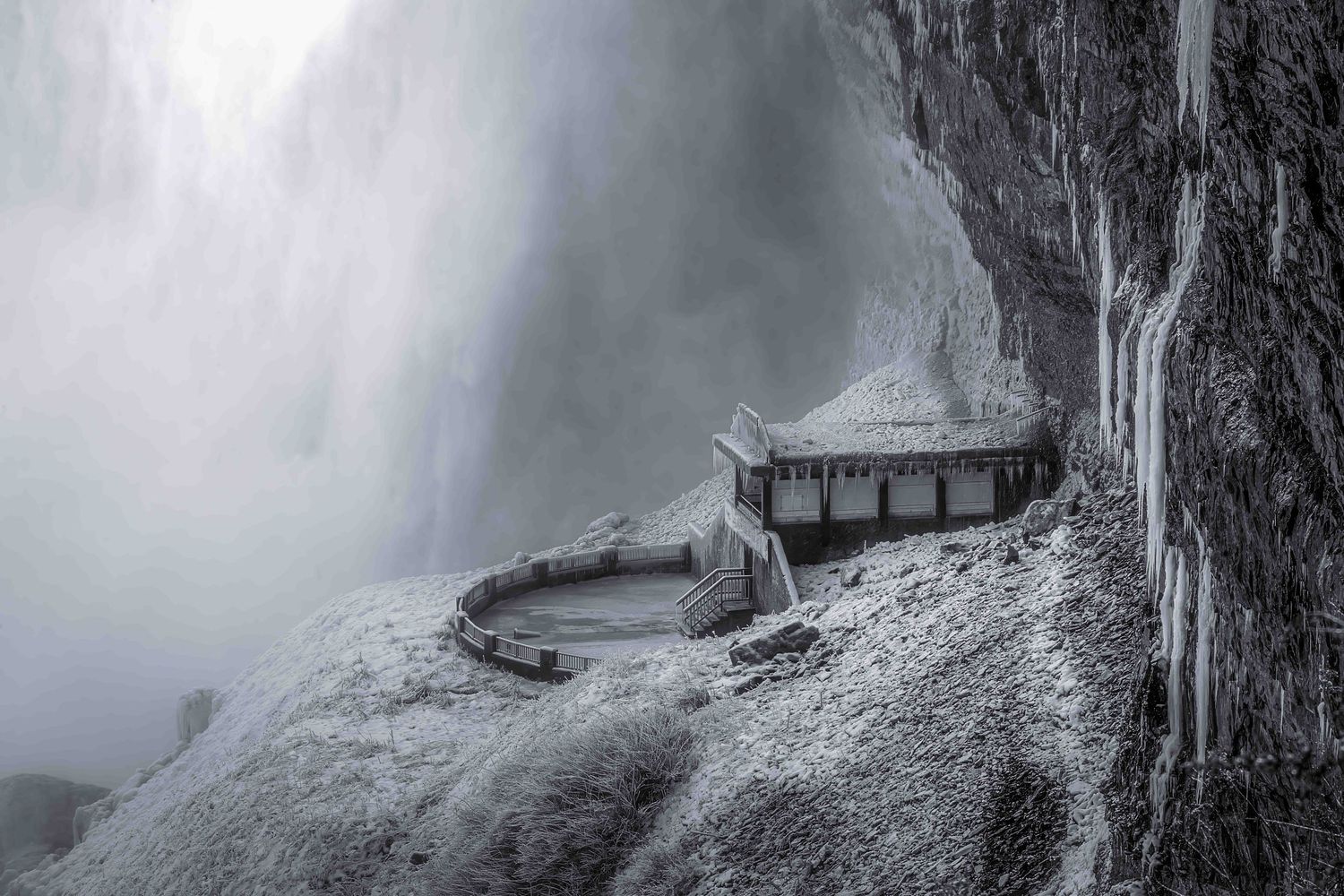 Small building is ice-covered, as Niagara Falls cascades behind for a wintery, ethereal image.