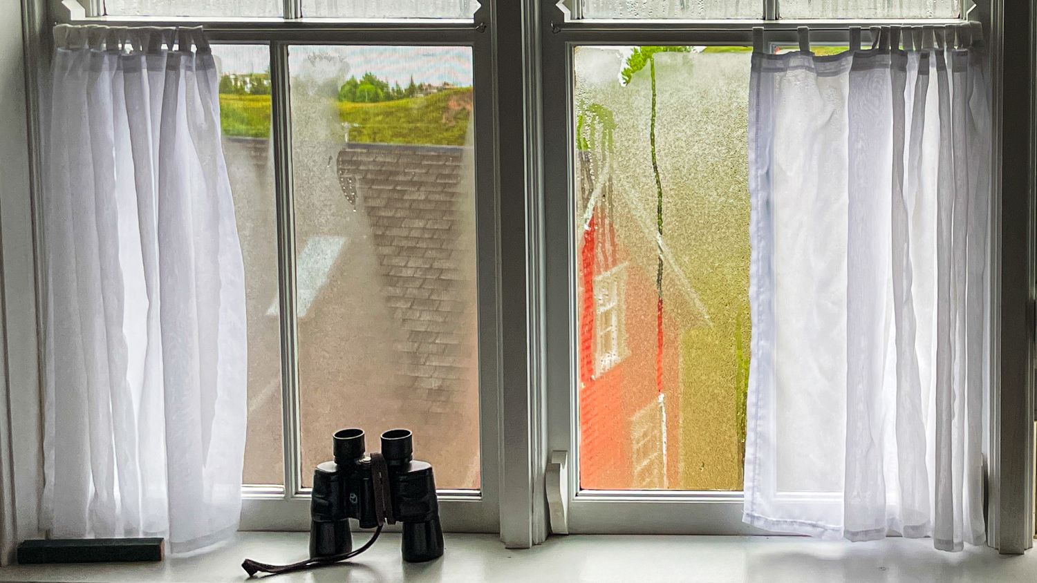 Modern interior window view with white curtains and natural daylight.