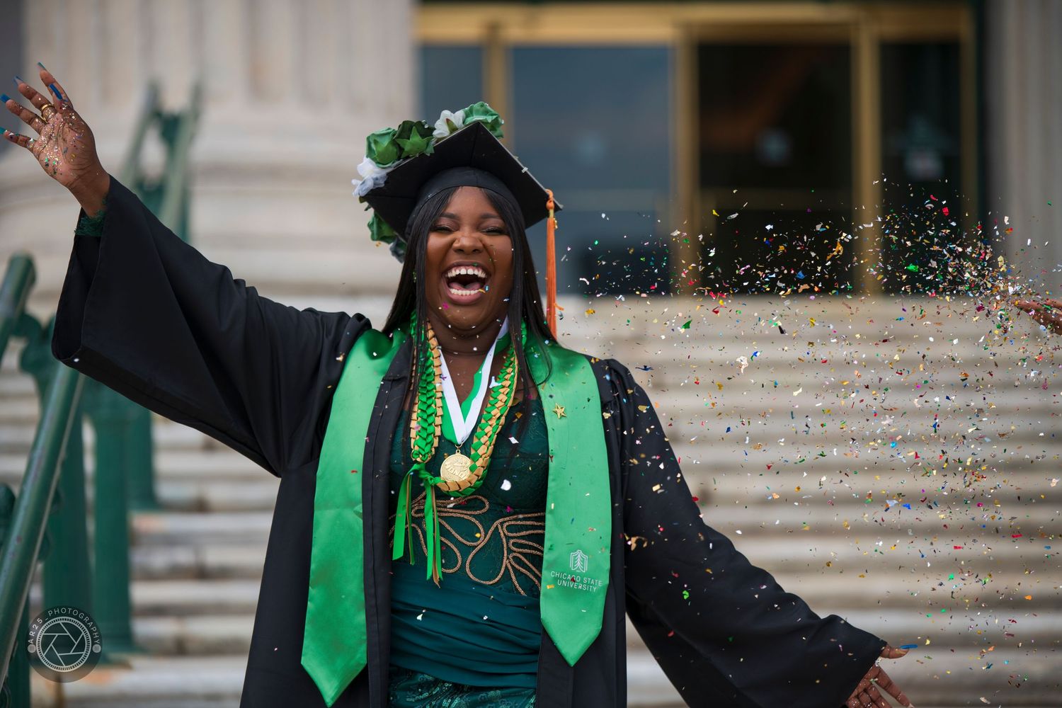 Graduate in cap and gown celebrating in confetti on the university steps