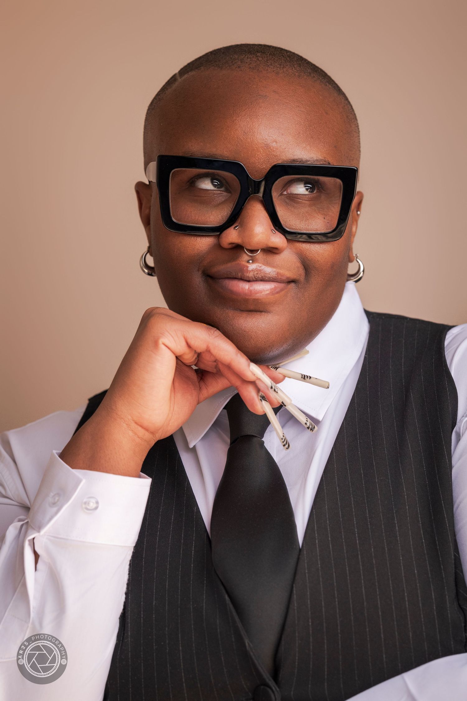 Professional headshot in a pinstripe waistcoat and black tie against a warm studio backdrop