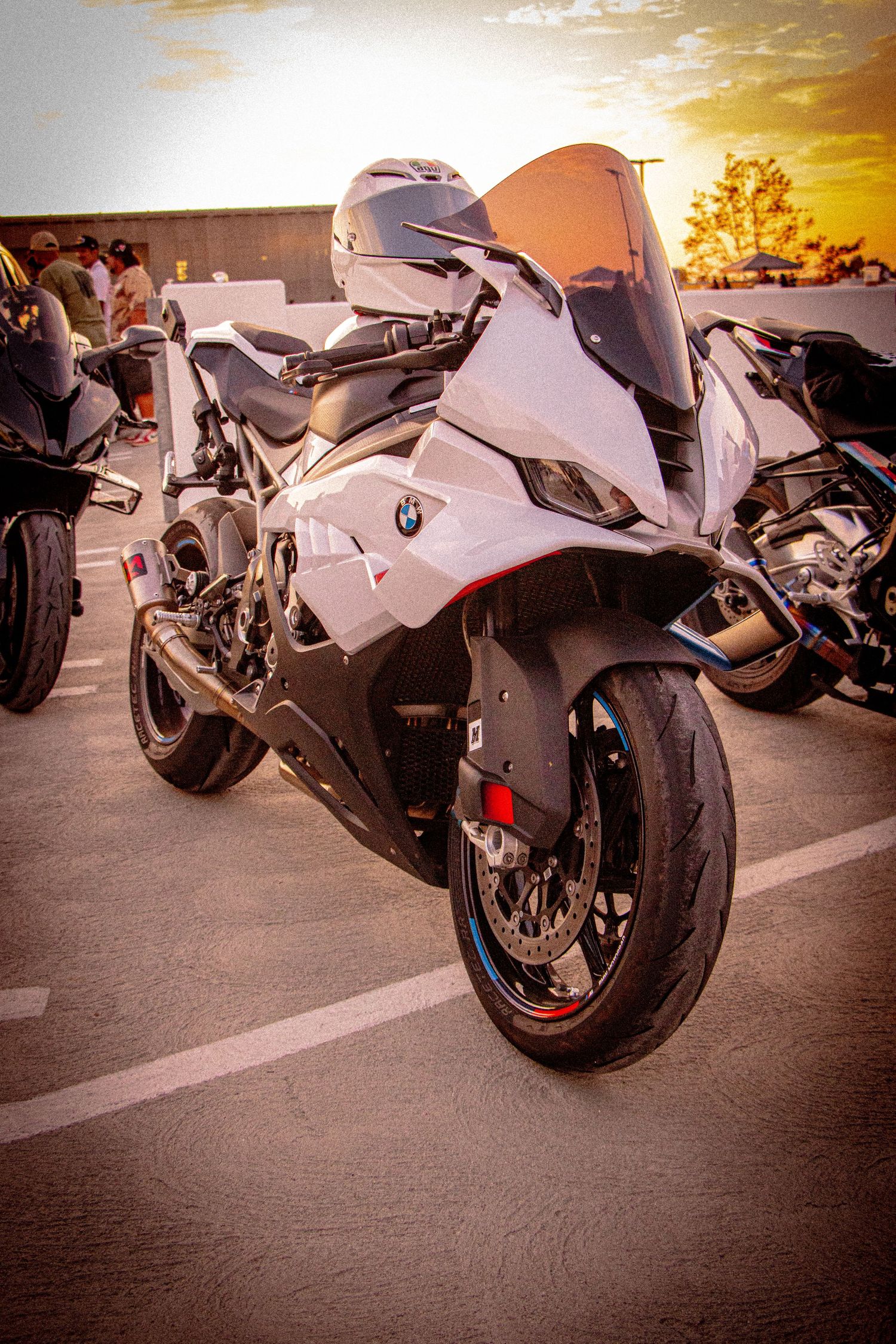 White BMW S1000RR sport motorcycle parked in a lot at sunset, showcasing its sleek fairing and aggressive design.