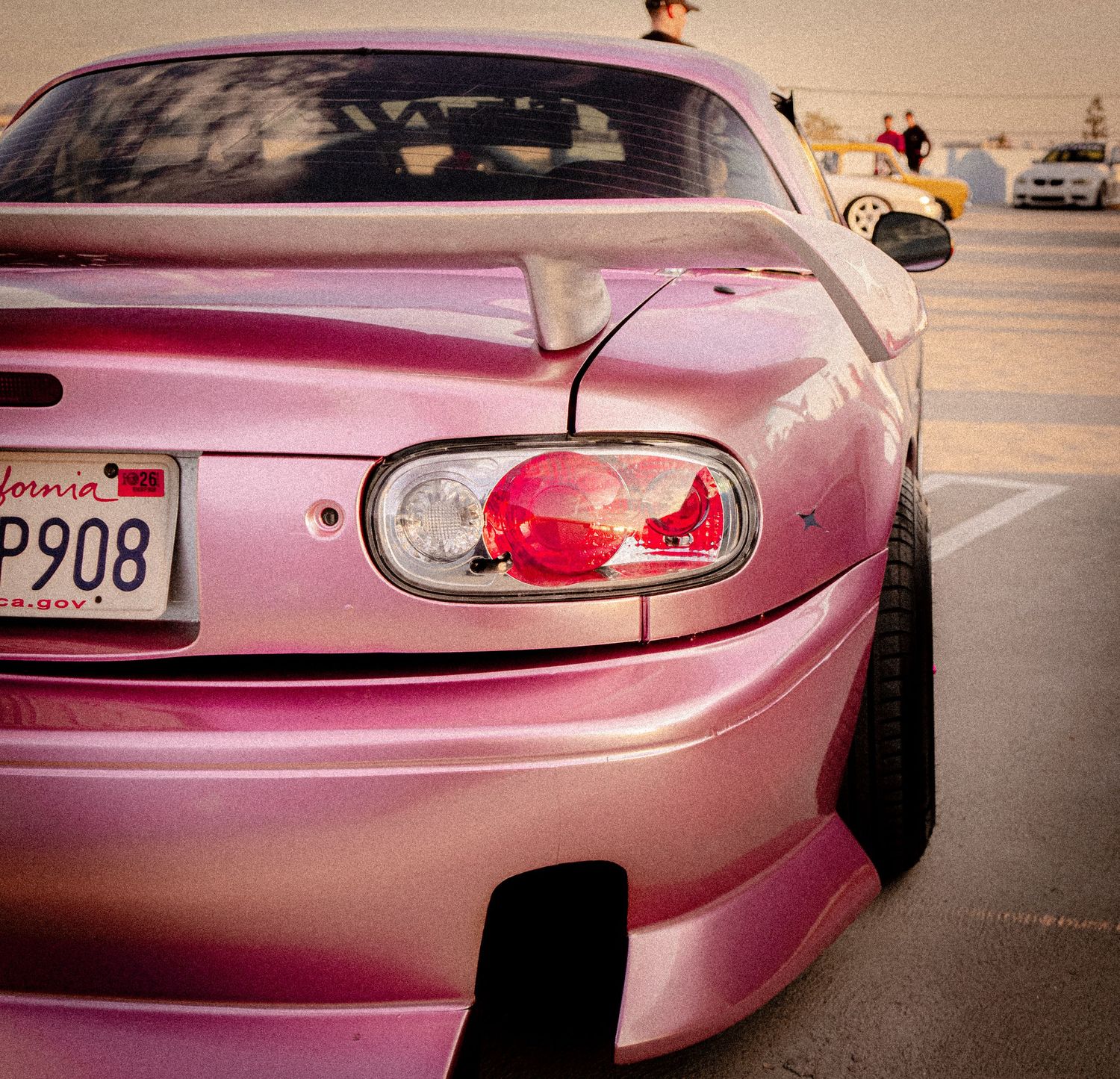 Pink Toyota Supra with California license plate P908 photographed from rear at a car show parking lot.