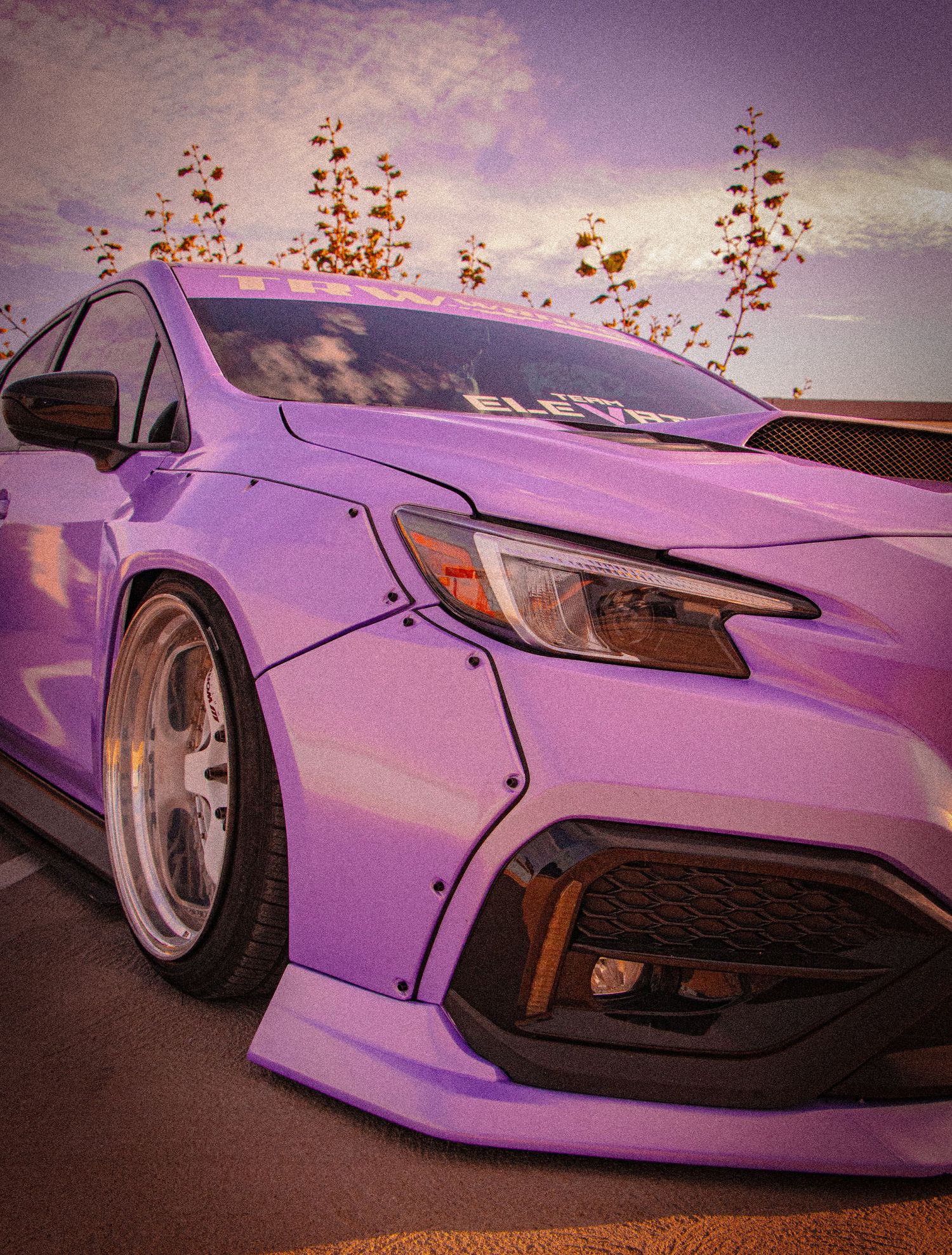 Purple widebody modified Honda Civic with aggressive body kit, deep dish wheels, and lowered stance at a car show.