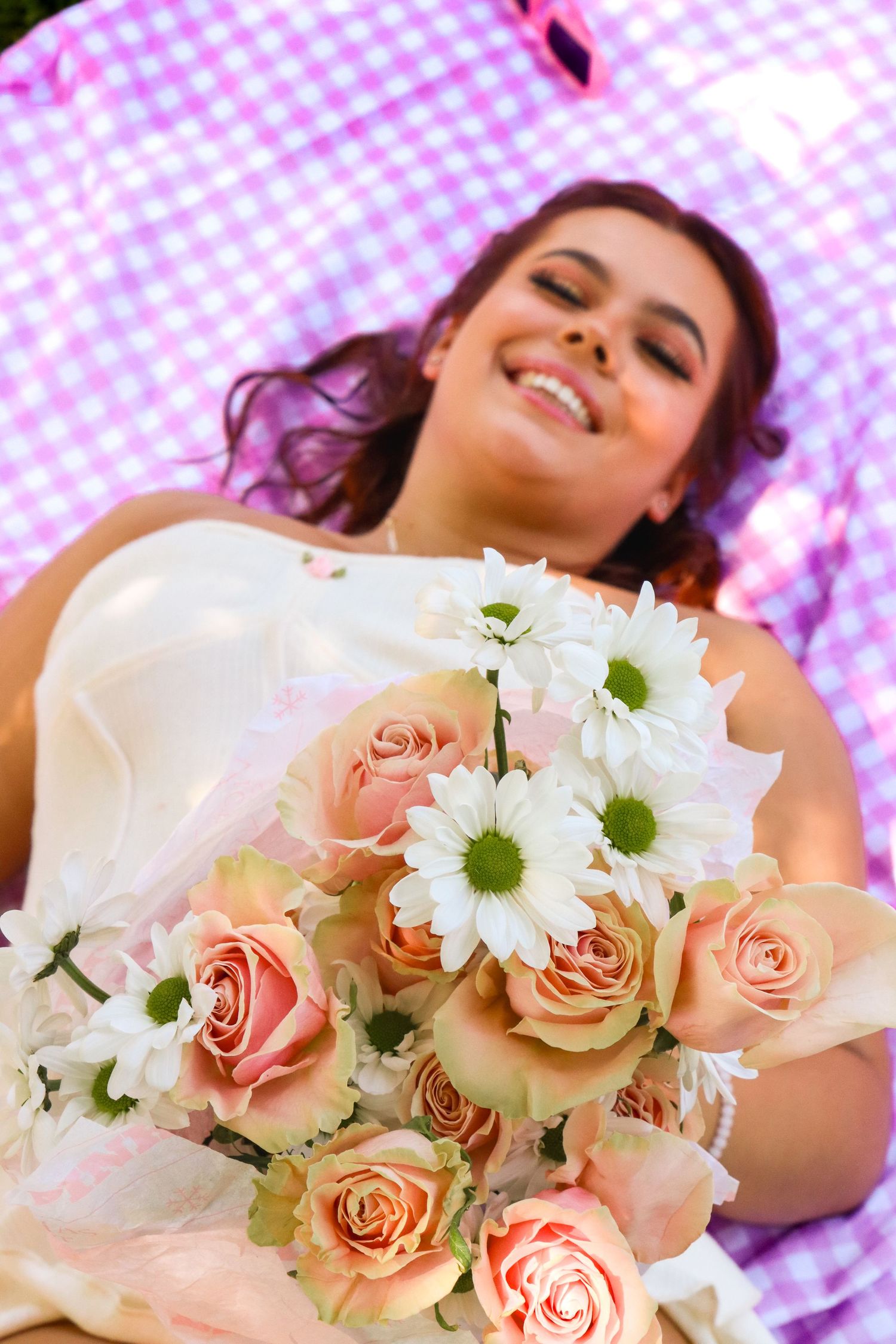 Beautiful bridal bouquet with pink roses and white daisies against purple backdrop.