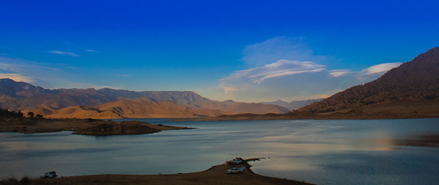 Scenic mountain lake landscape with blue water and rugged terrain under clear skies.