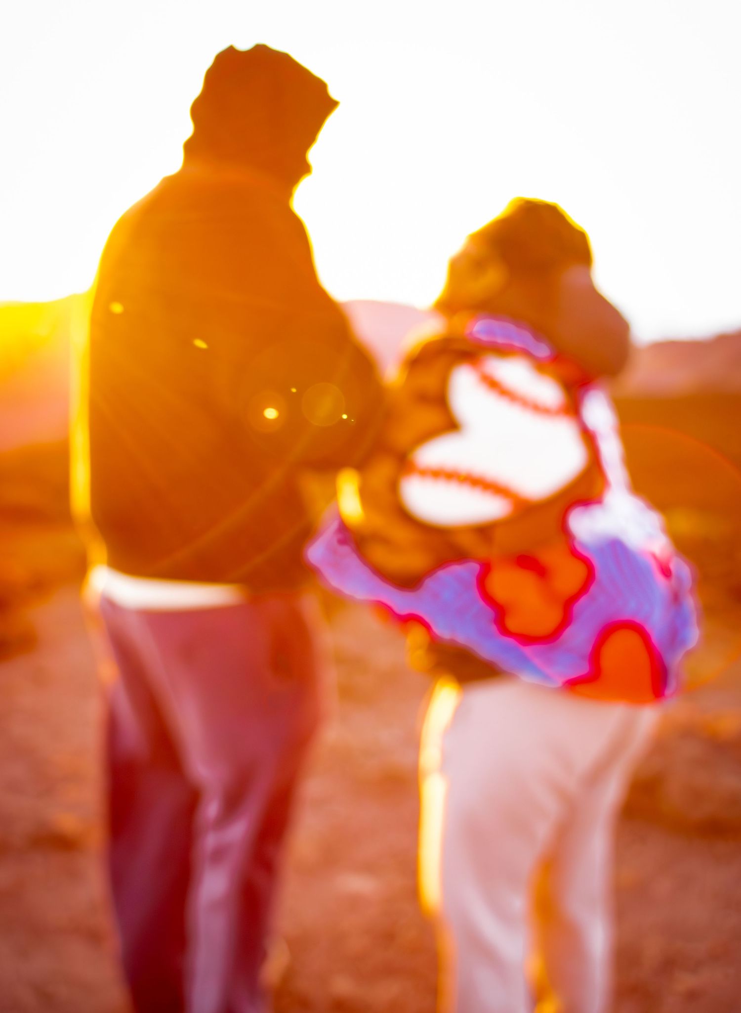 Silhouettes of two people standing in golden sunset light.