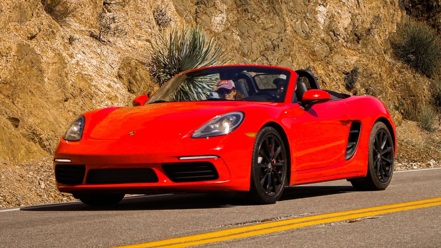 Line of red Ferrari supercars positioned along a scenic mountain road.