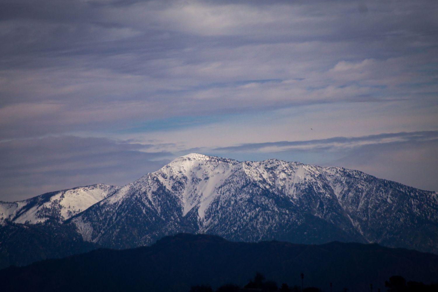 Snow-capped mountain peak under dramatic cloudy sky.