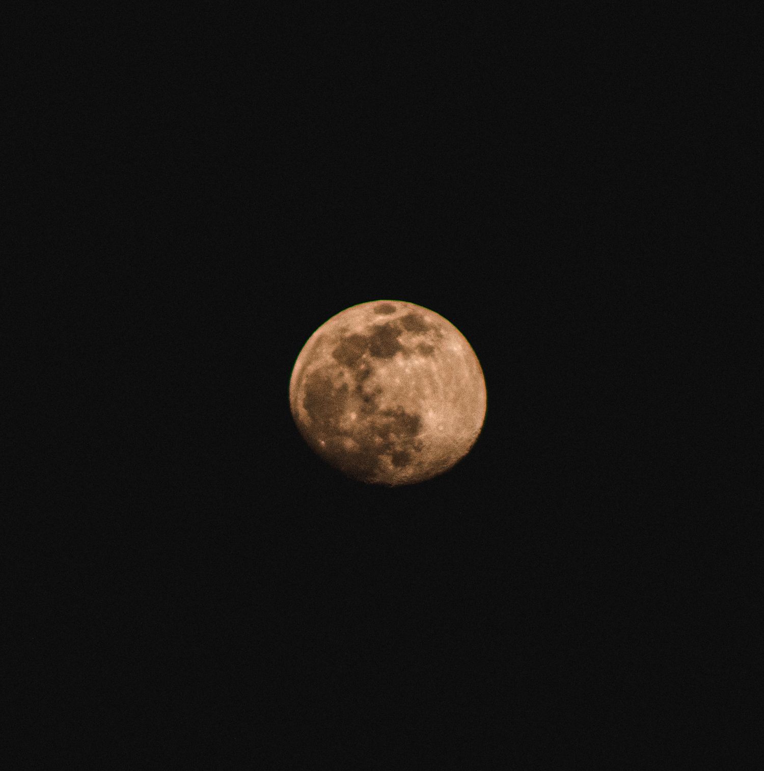 Full moon glowing with an orange hue against a dark night sky.