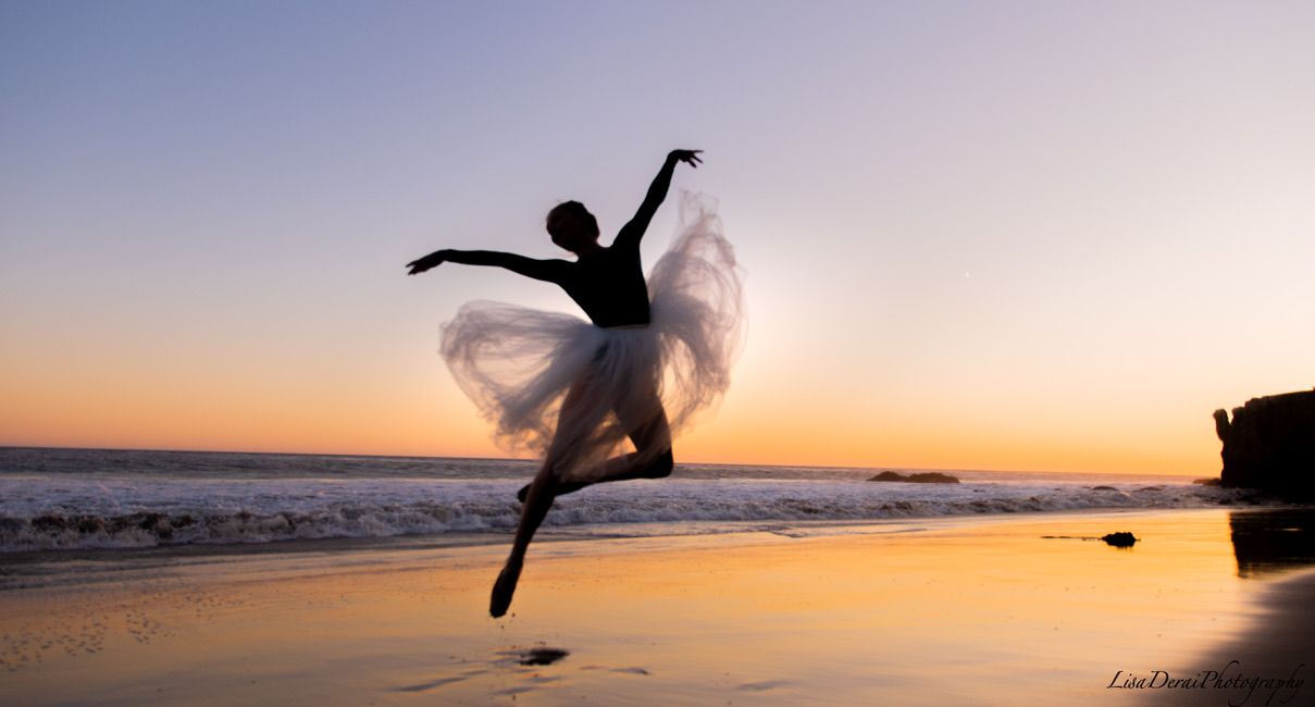Silhouette of a dancer leaping gracefully against a sunset beach backdrop.