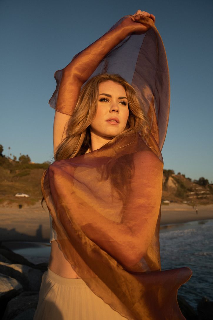Golden hour beach portraits with sheer fabric creating dramatic silhouettes.