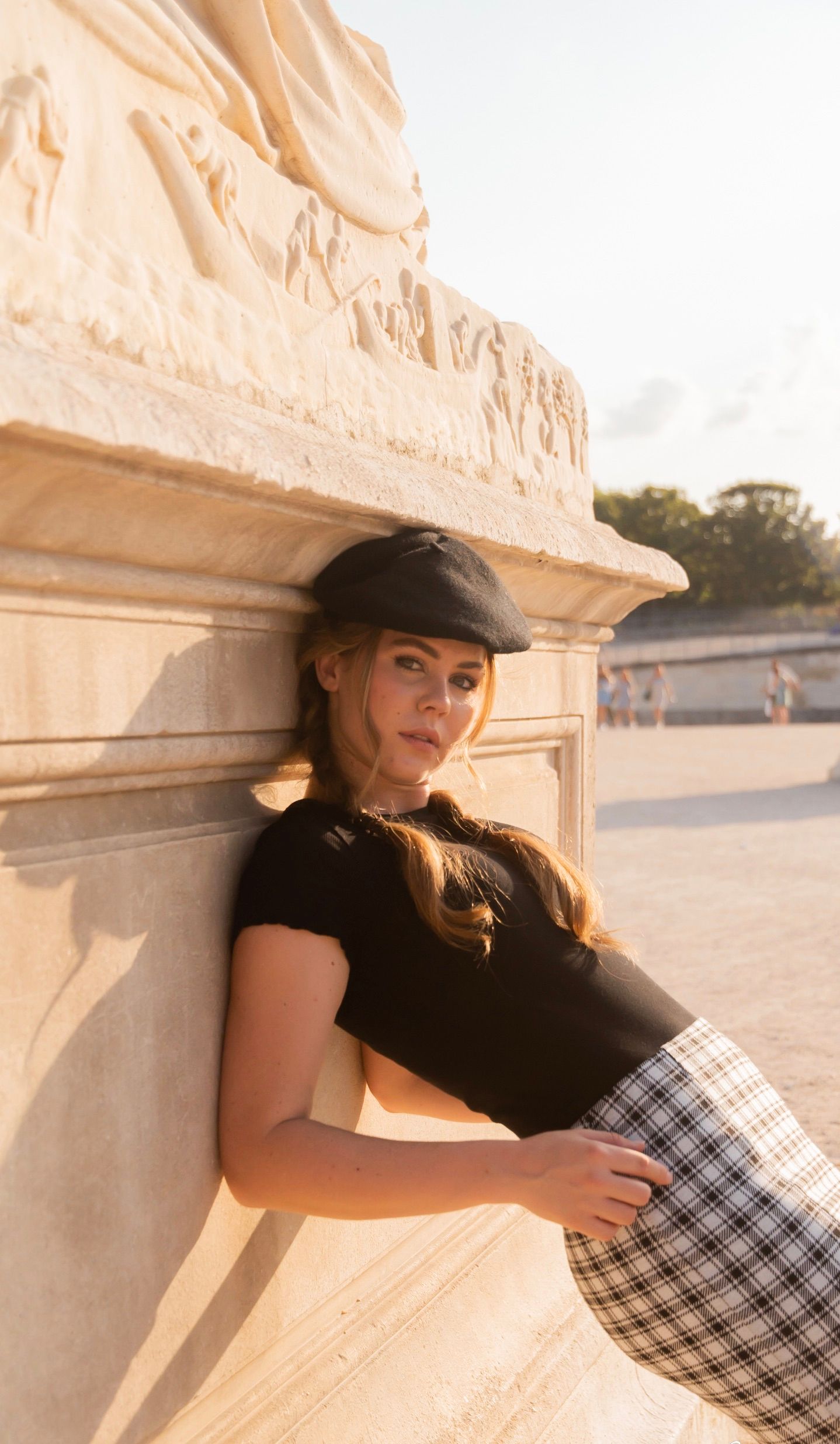 Artistic portrait session against cream colored stone wall in warm sunset lighting.