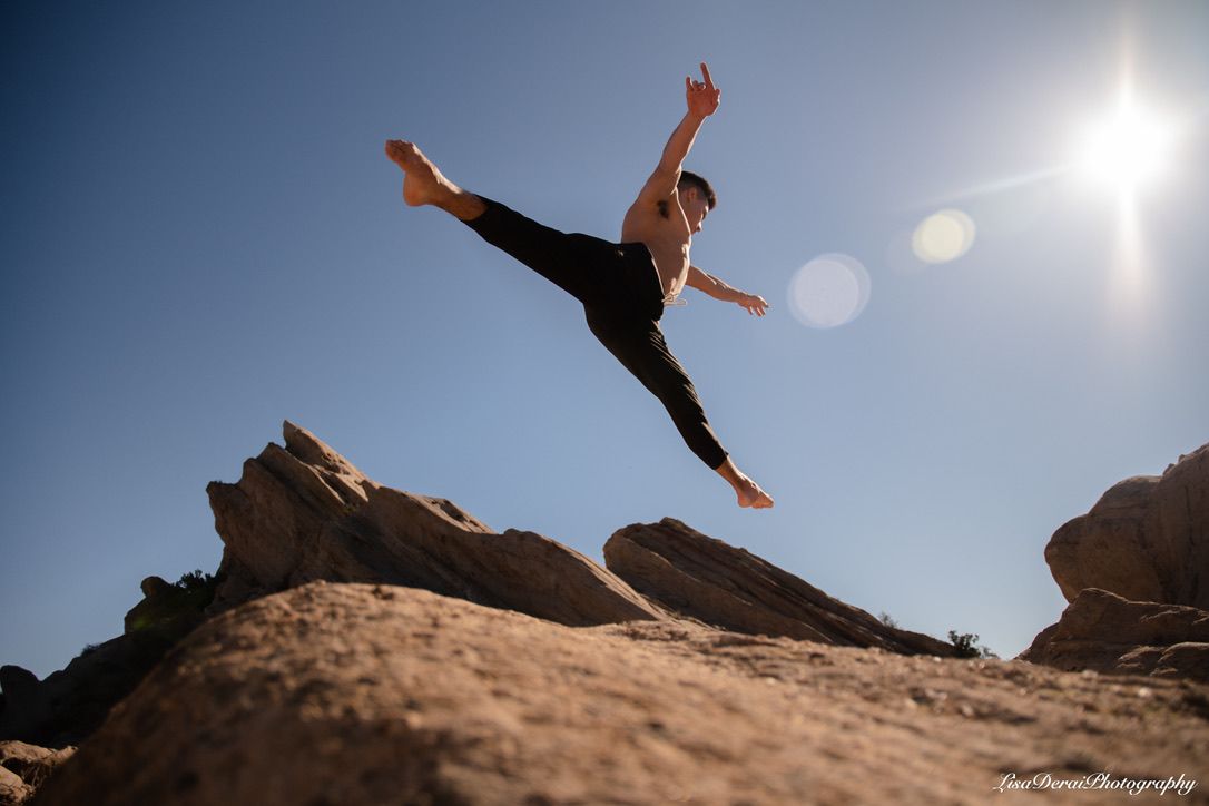 Mid-air split jump photographed against desert rock formations.
