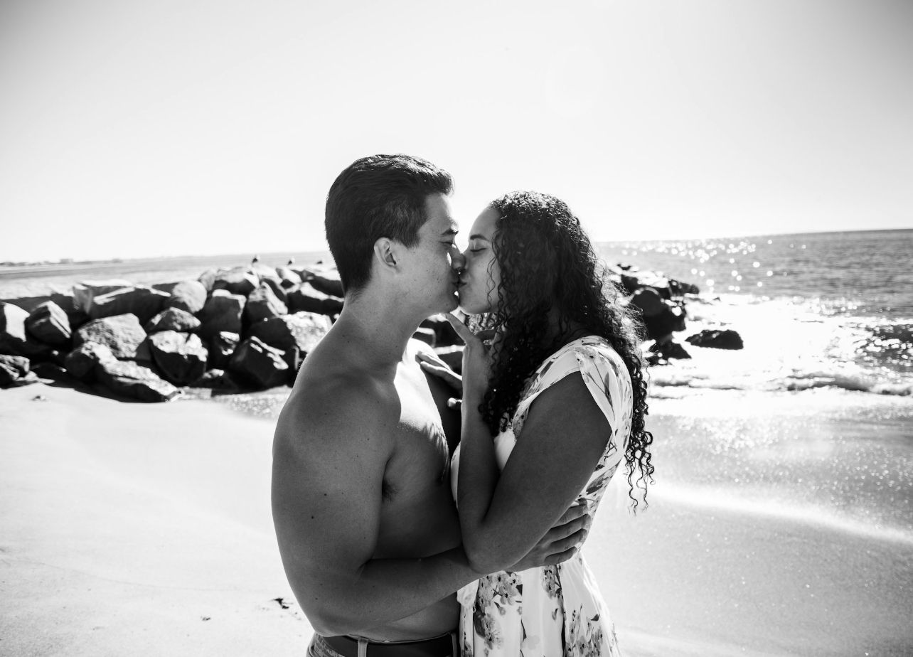 Romantic black and white beach photo shoot with couple on rocks.