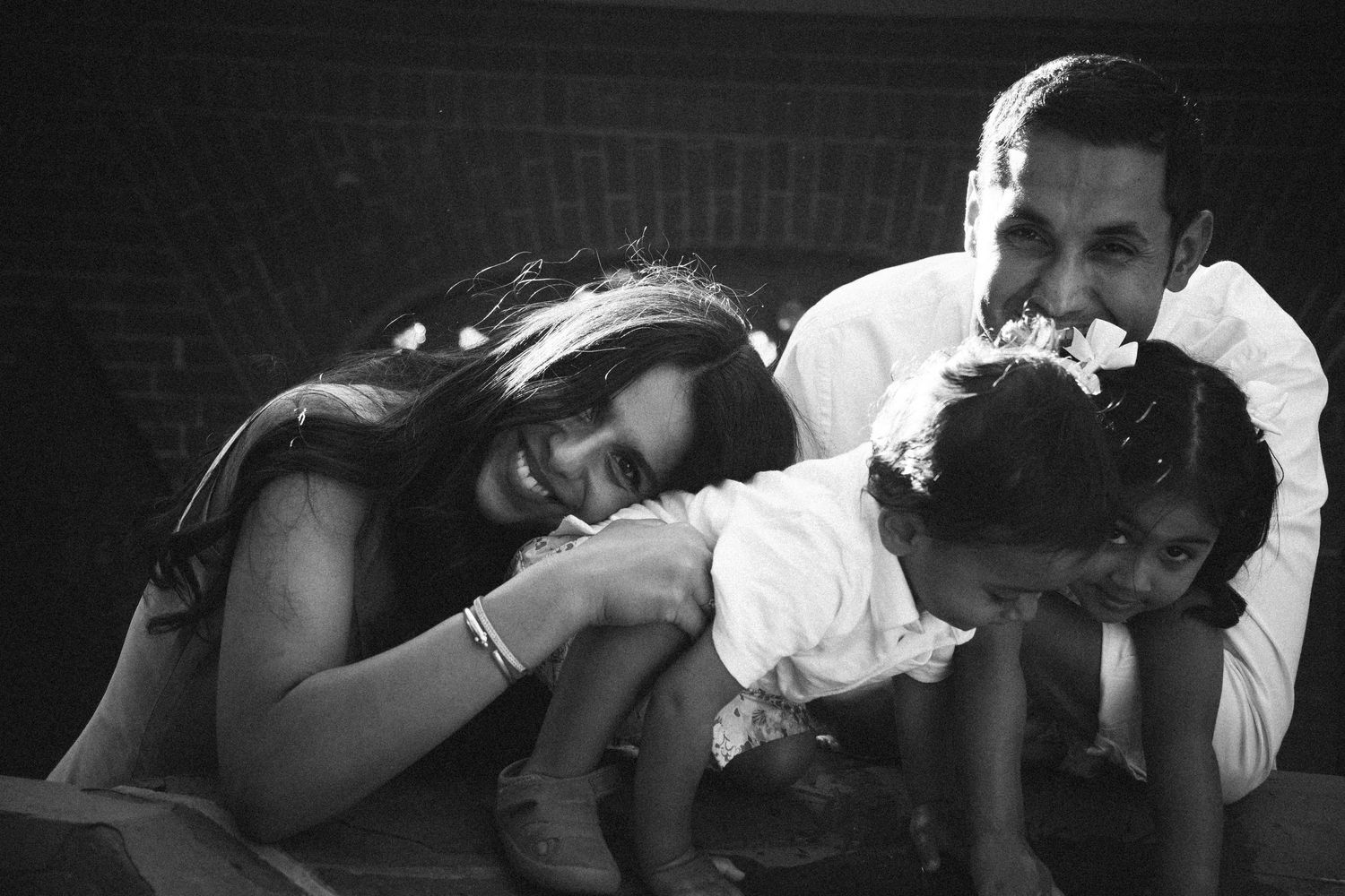 Black and white family photo of parents and two young children playing together on the floor.