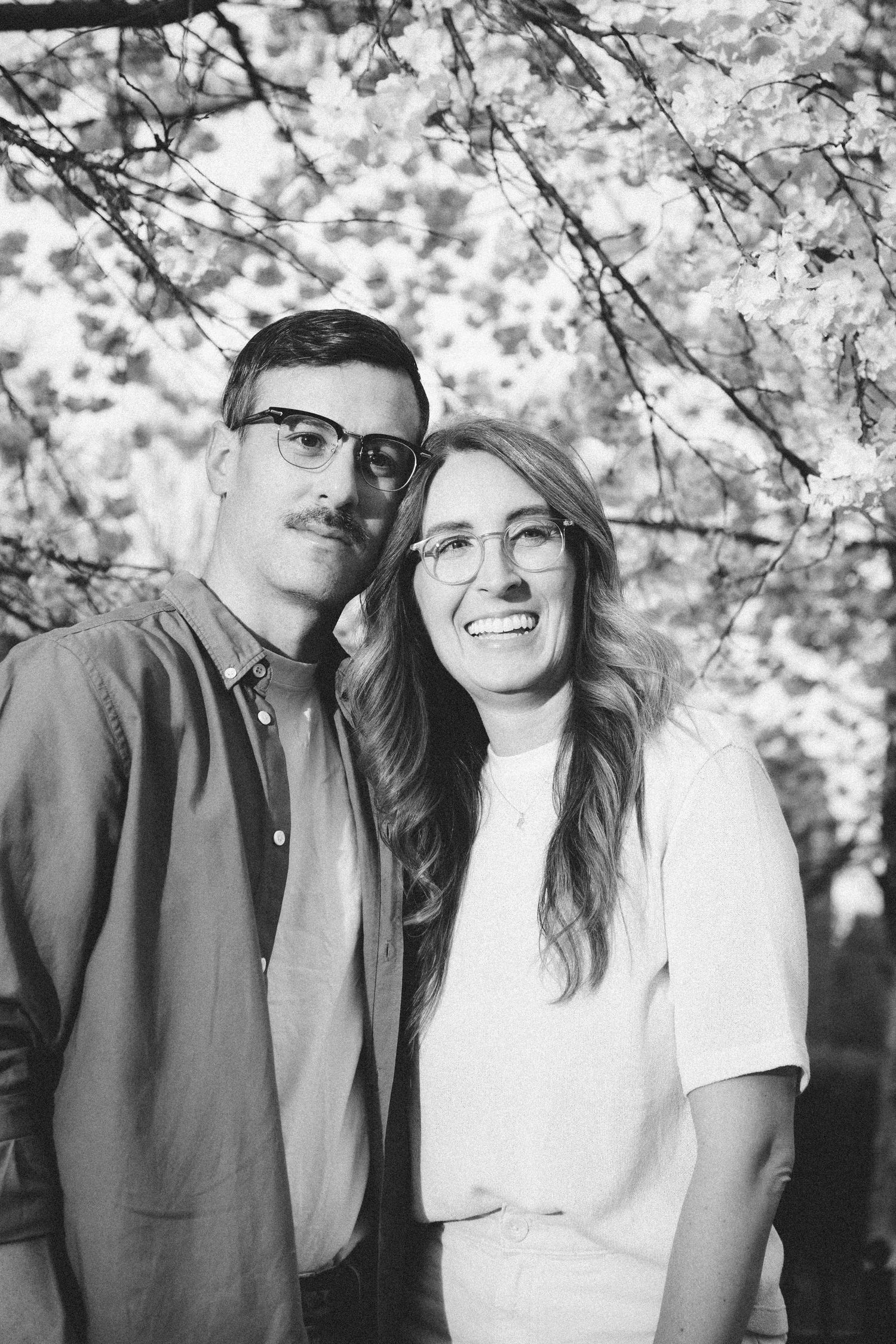 Black and white intimate portraits captured under flowering cherry blossom branches.