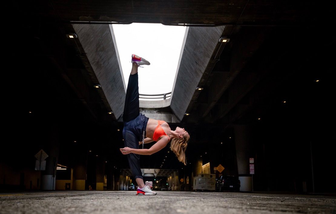 Dancer executes a fluid movement sequence in an industrial concrete space.