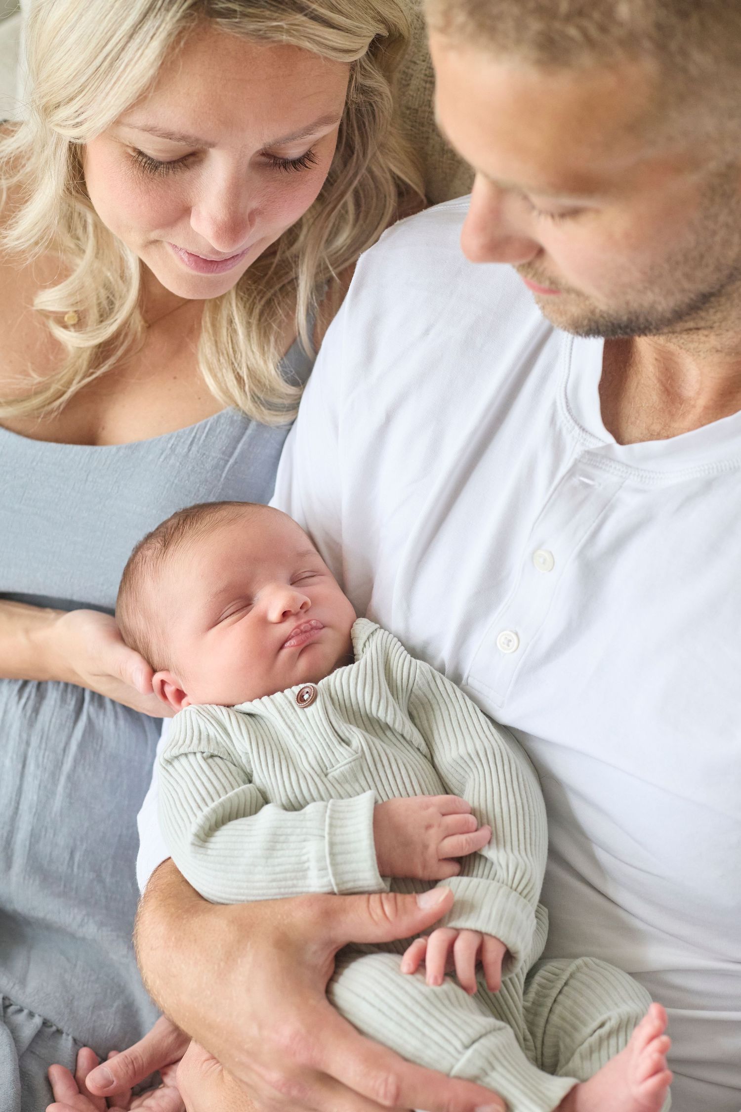 Newborn photo of mom and dad looking at new baby.