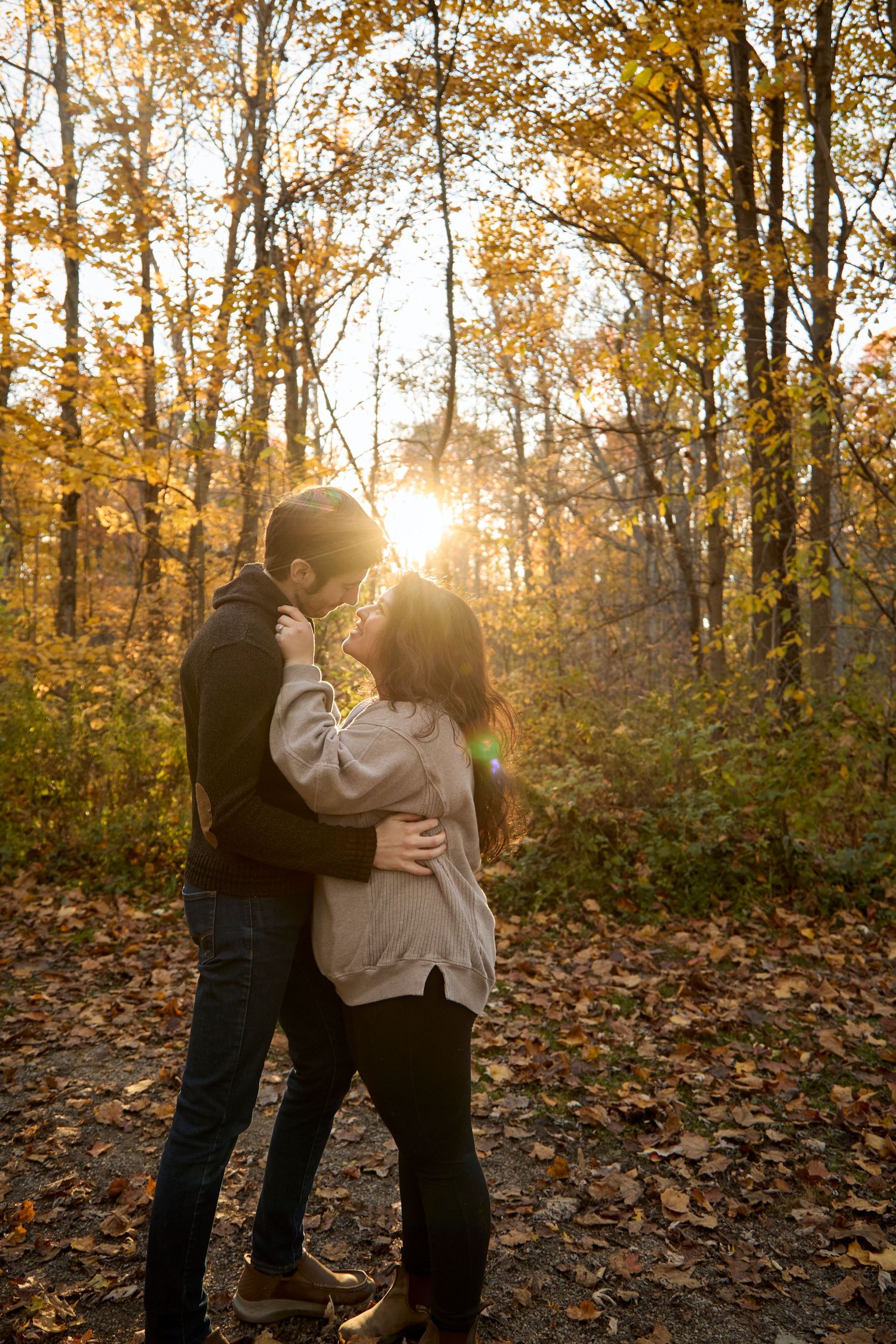Engaged couple in woods at golden hour.