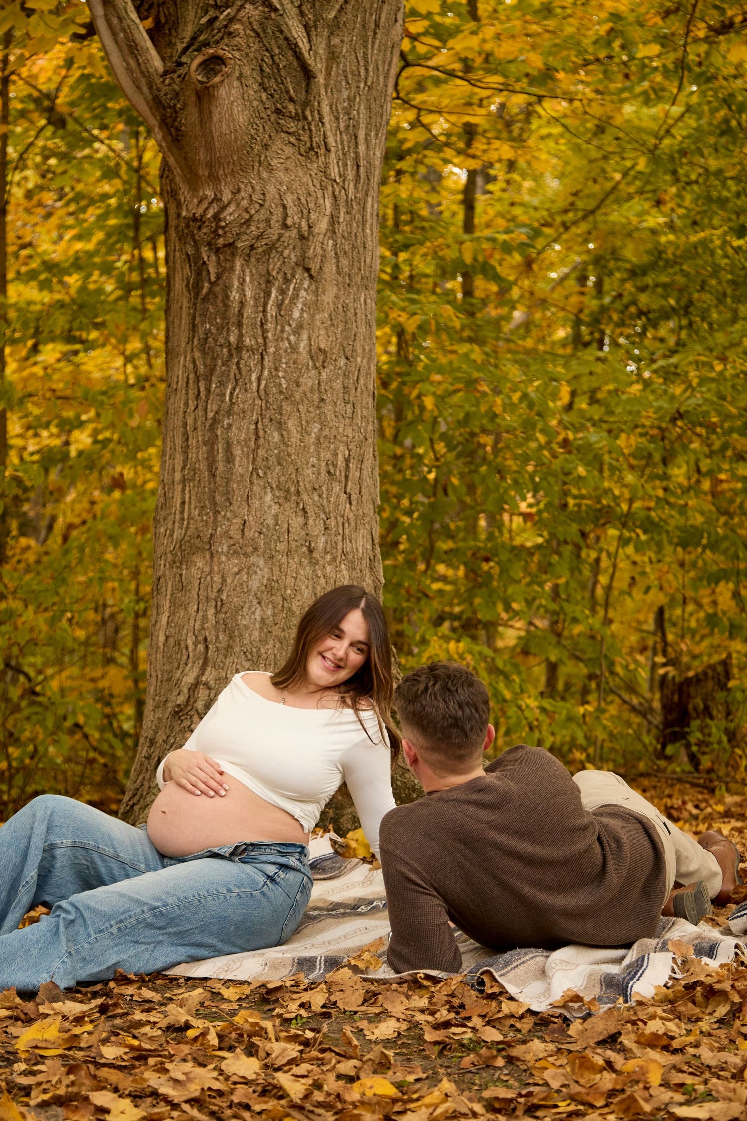 Maternity photo of mom and dad sitting in fall setting.