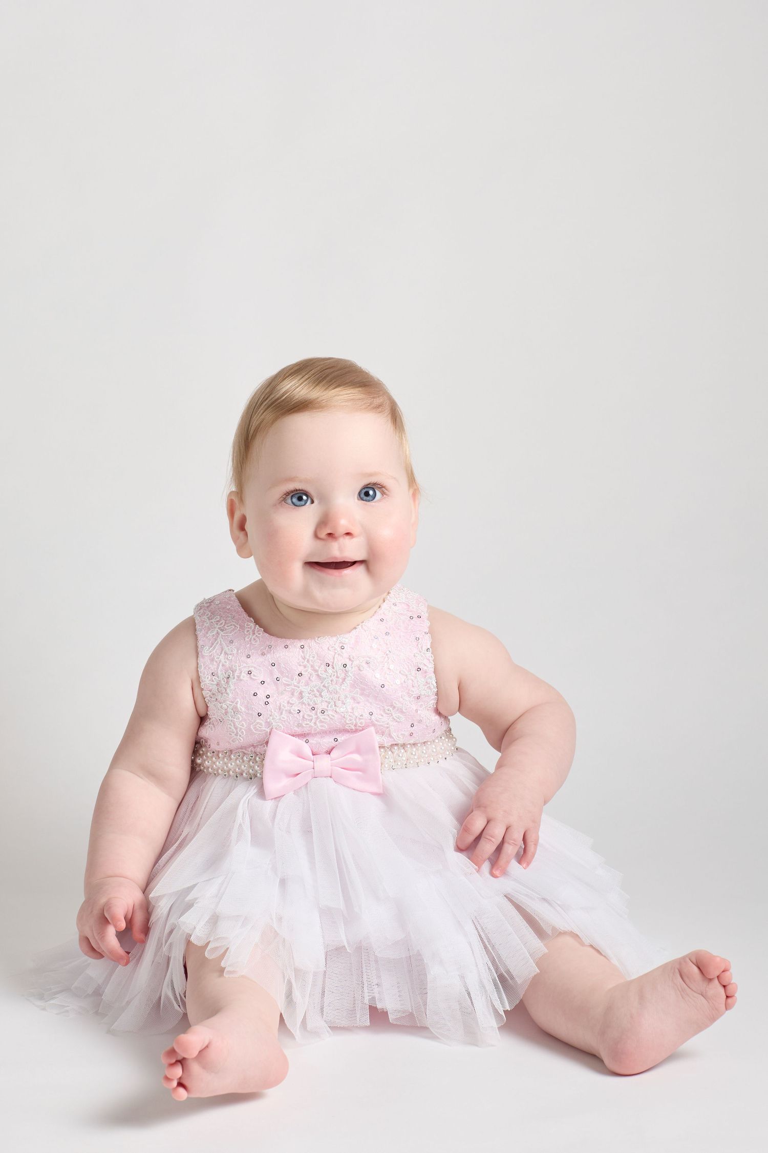 Baby in pink dress on white background.