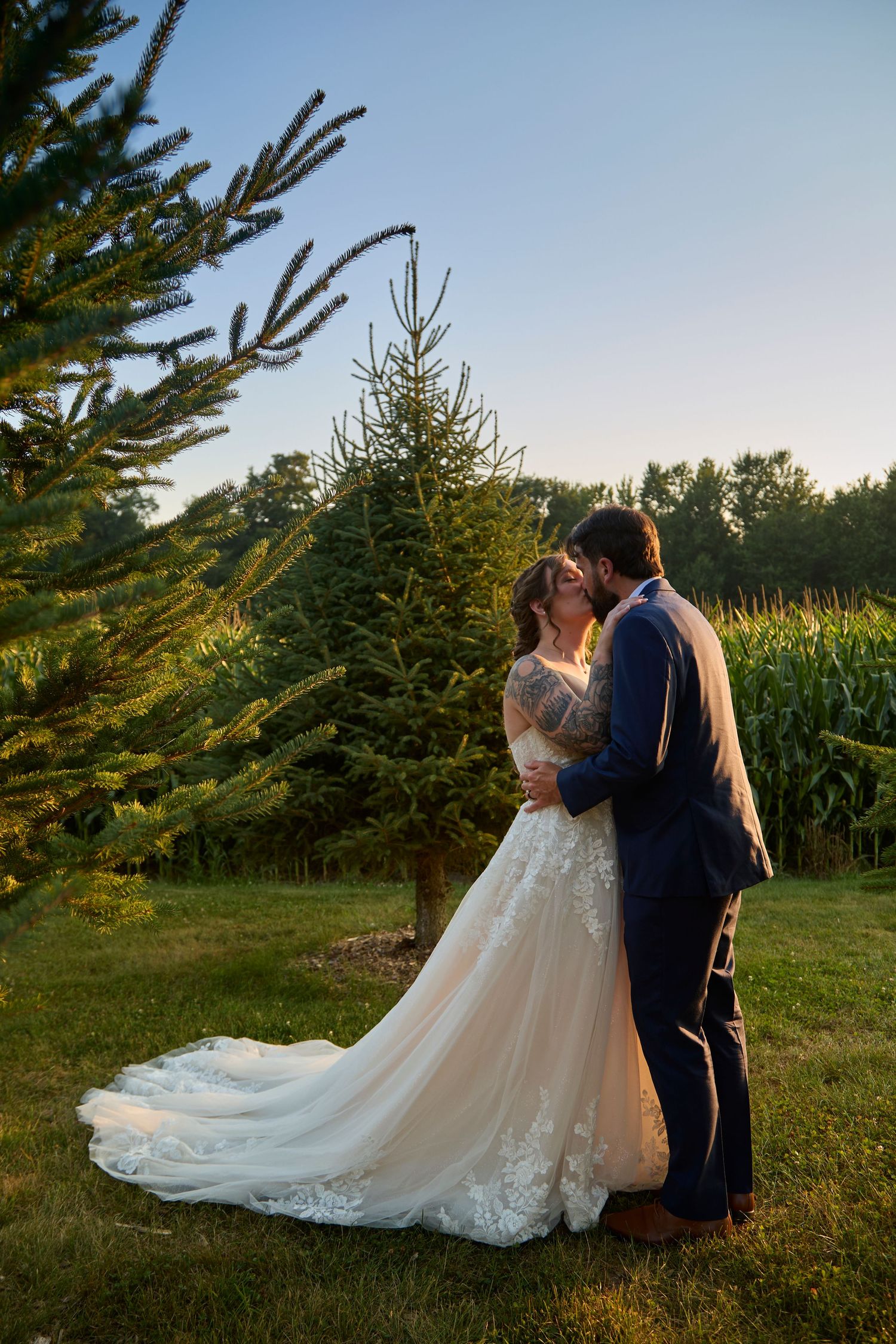 Bride and groom in evergreen trees at golden hour.