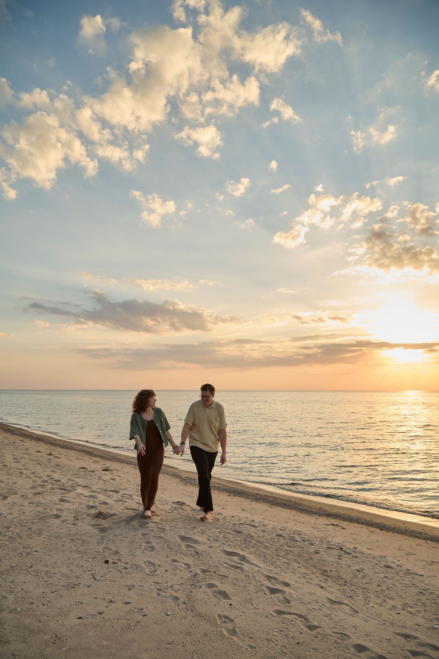 Engaged couple walking on beach in Bayfield at golden hour.