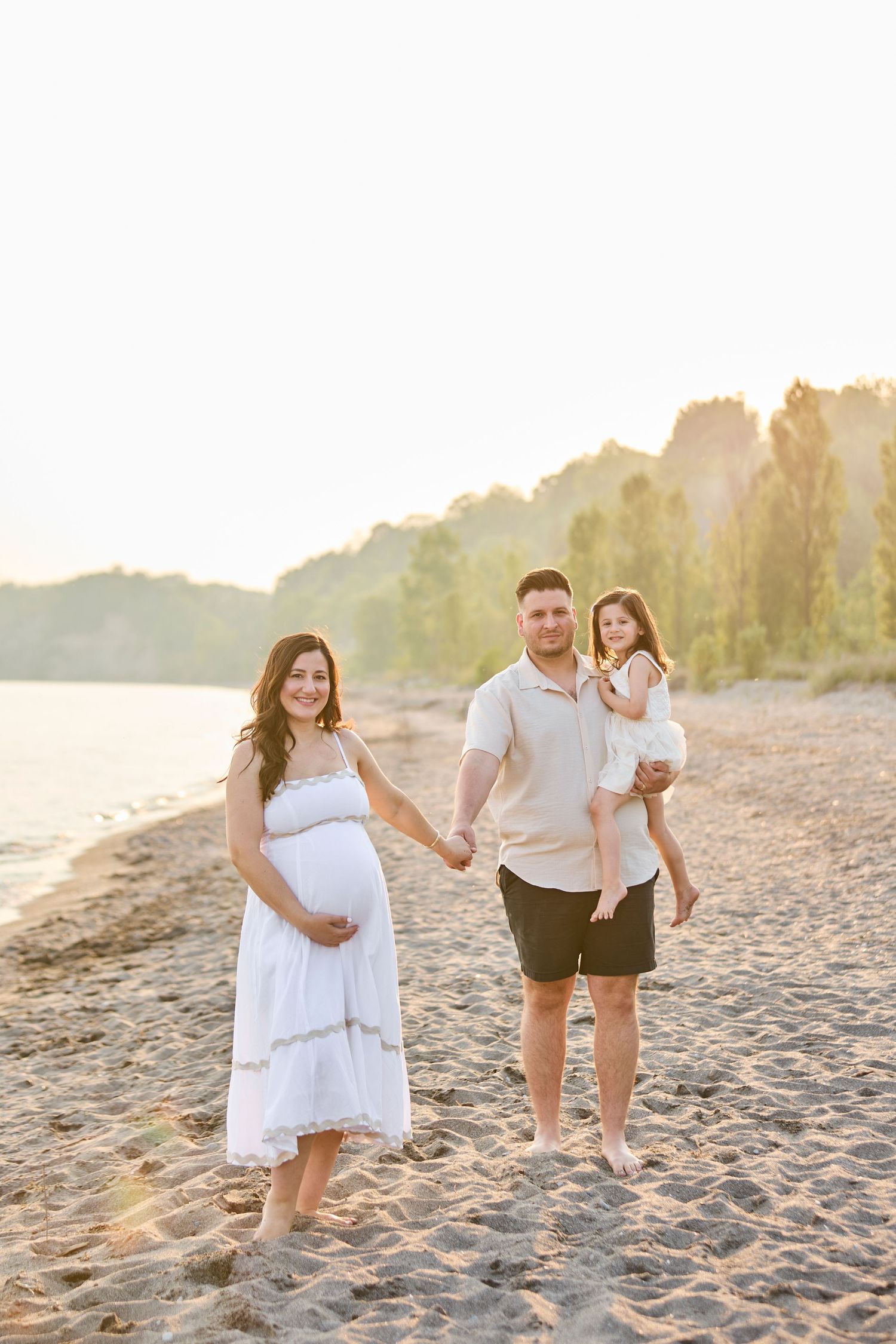 Family maternity photo on beach at sunset.