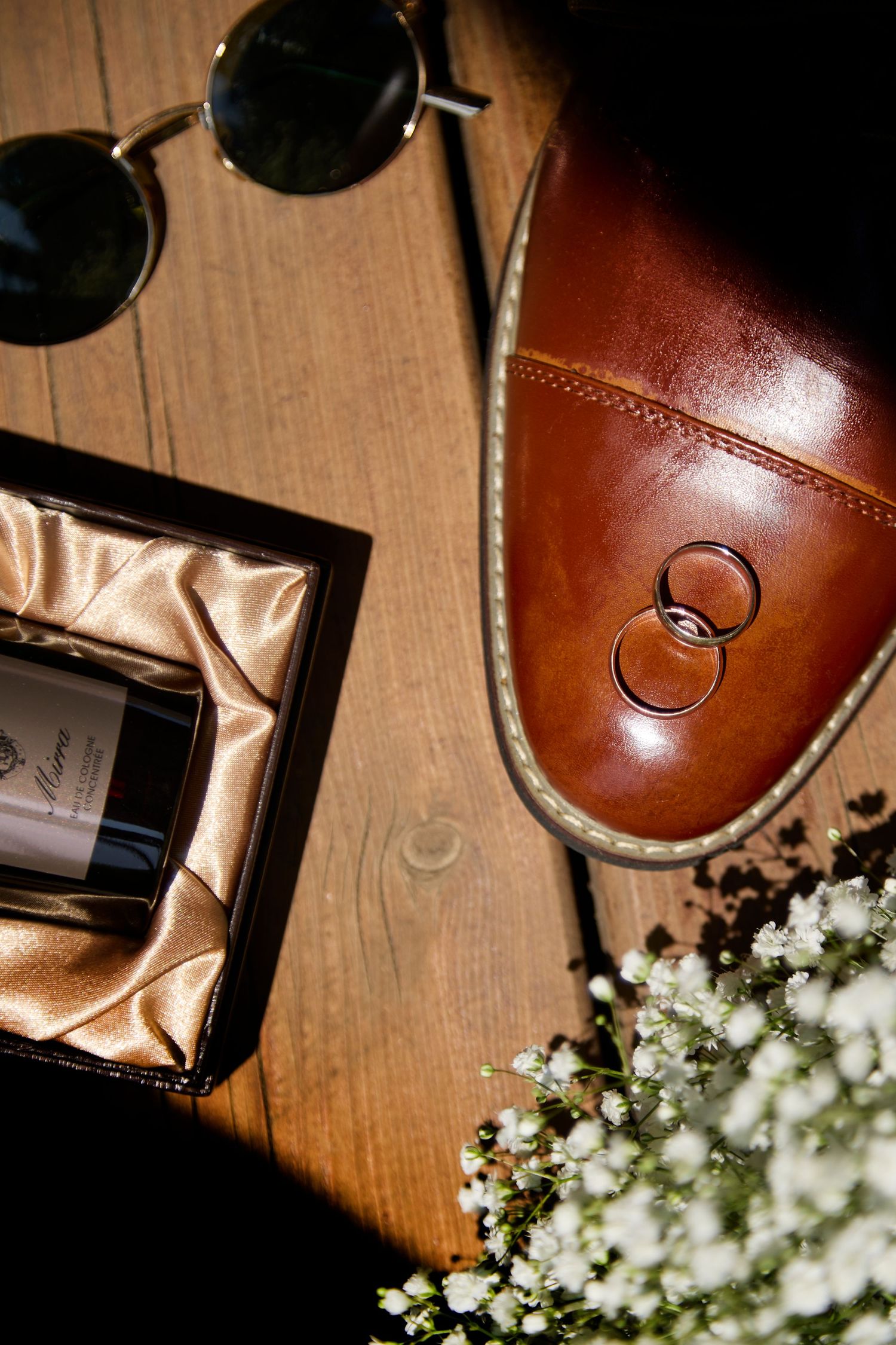 Layflat of shoes, florals, glasses and rings at wedding.