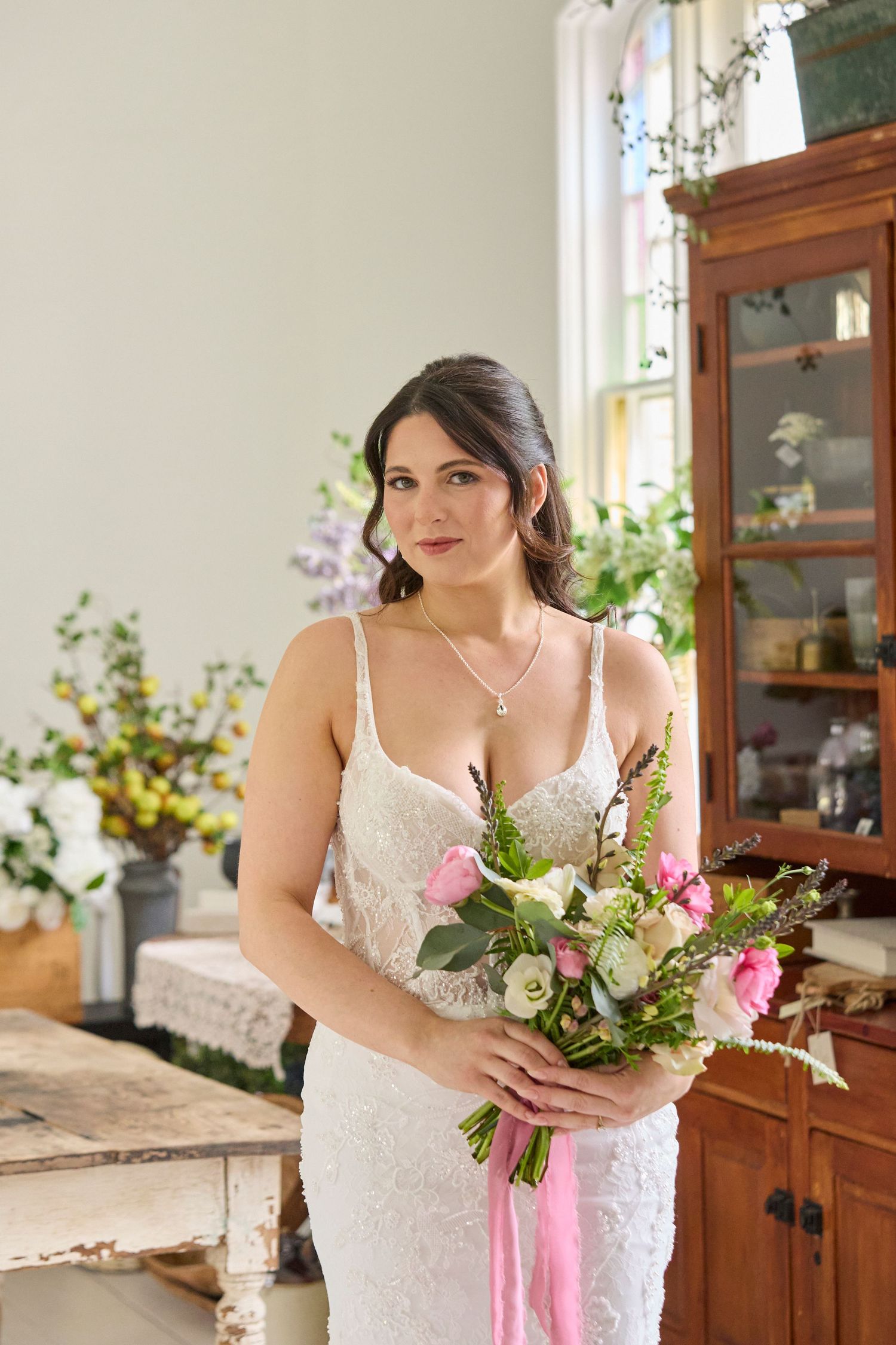 Bride standing in vintage setting with florals and stained glass.
