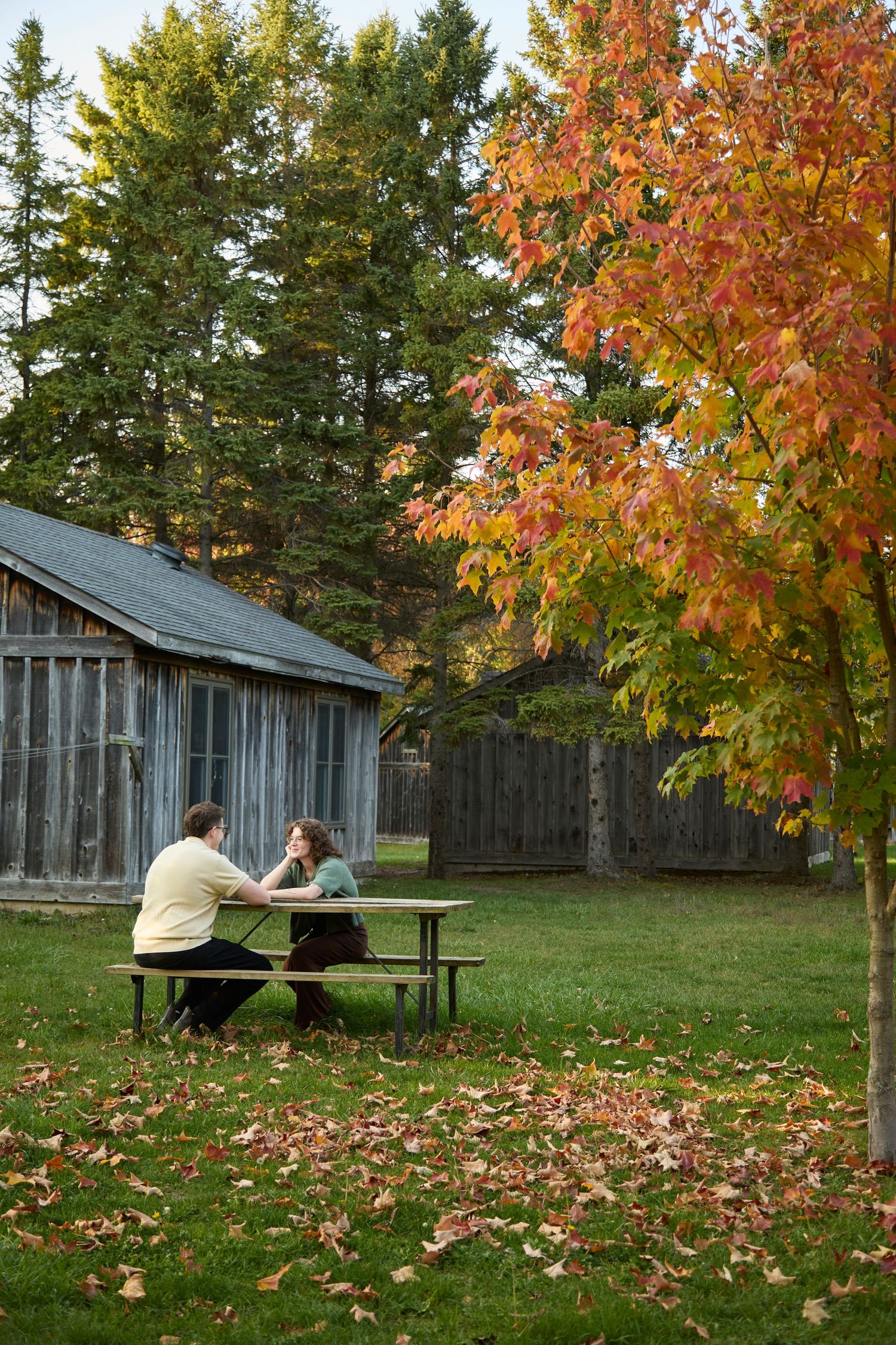 Couple on picnic table in fall setting.