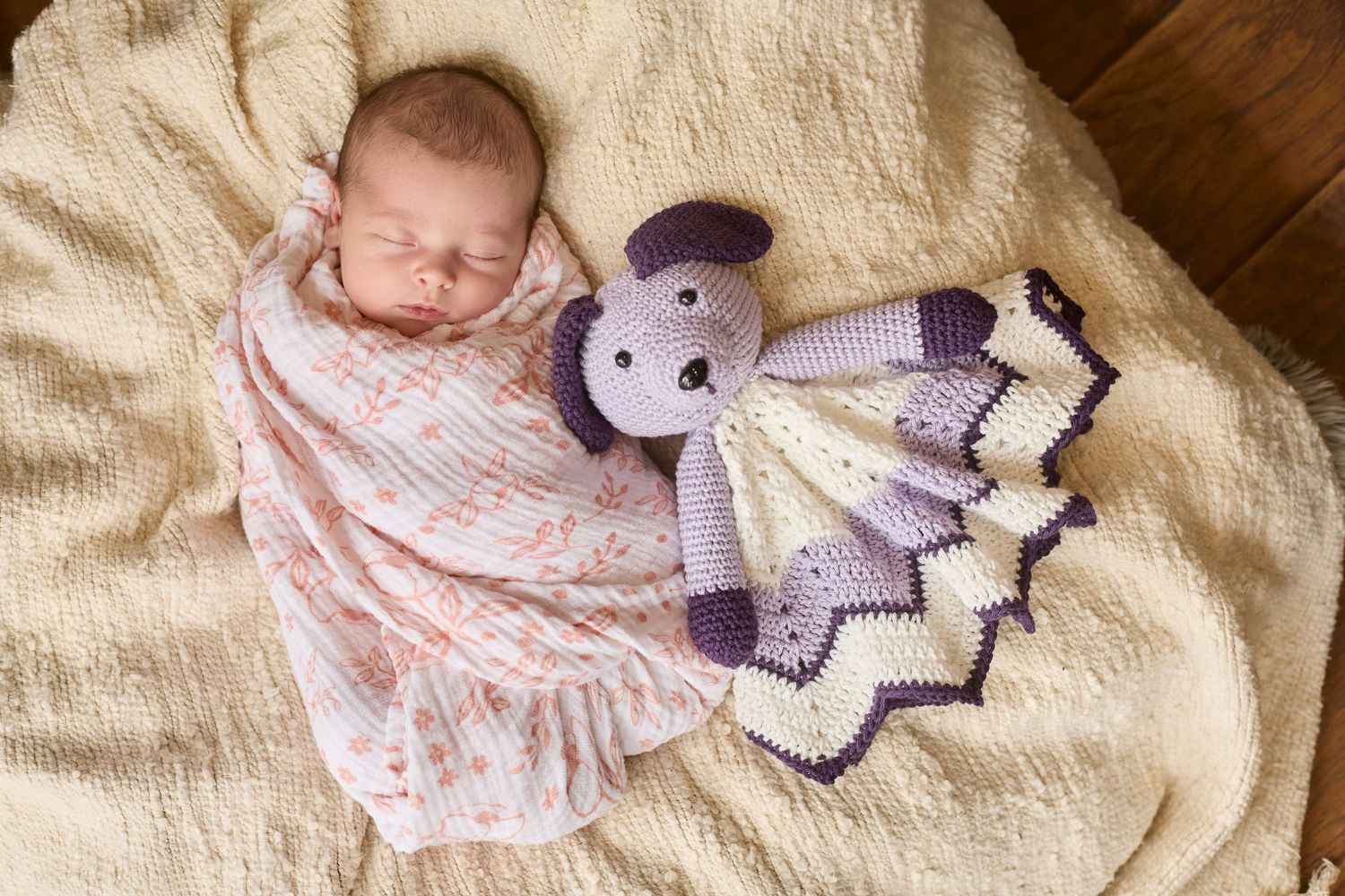 Newborn baby on white blanket with crochet toy.