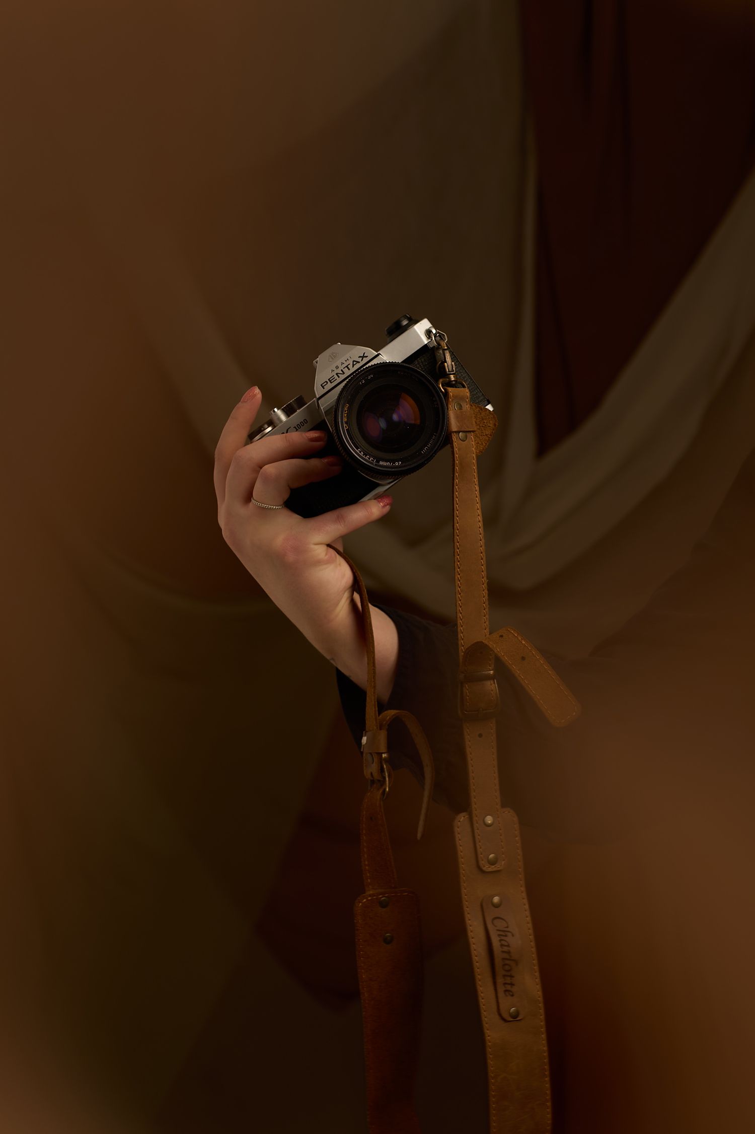 Branding image of film camera with leather strap.