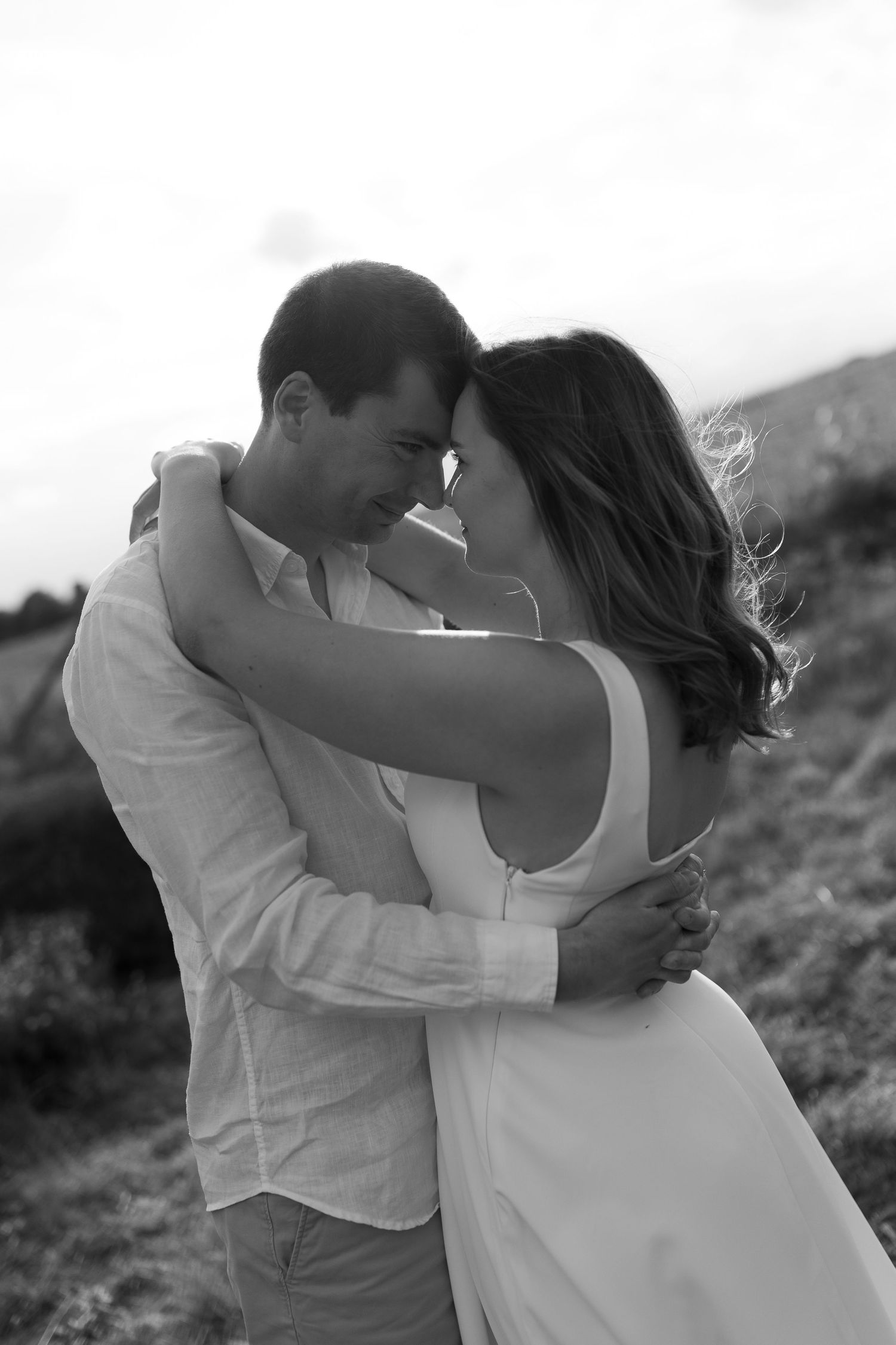 A couple embracing tenderly in a scenic outdoor setting.