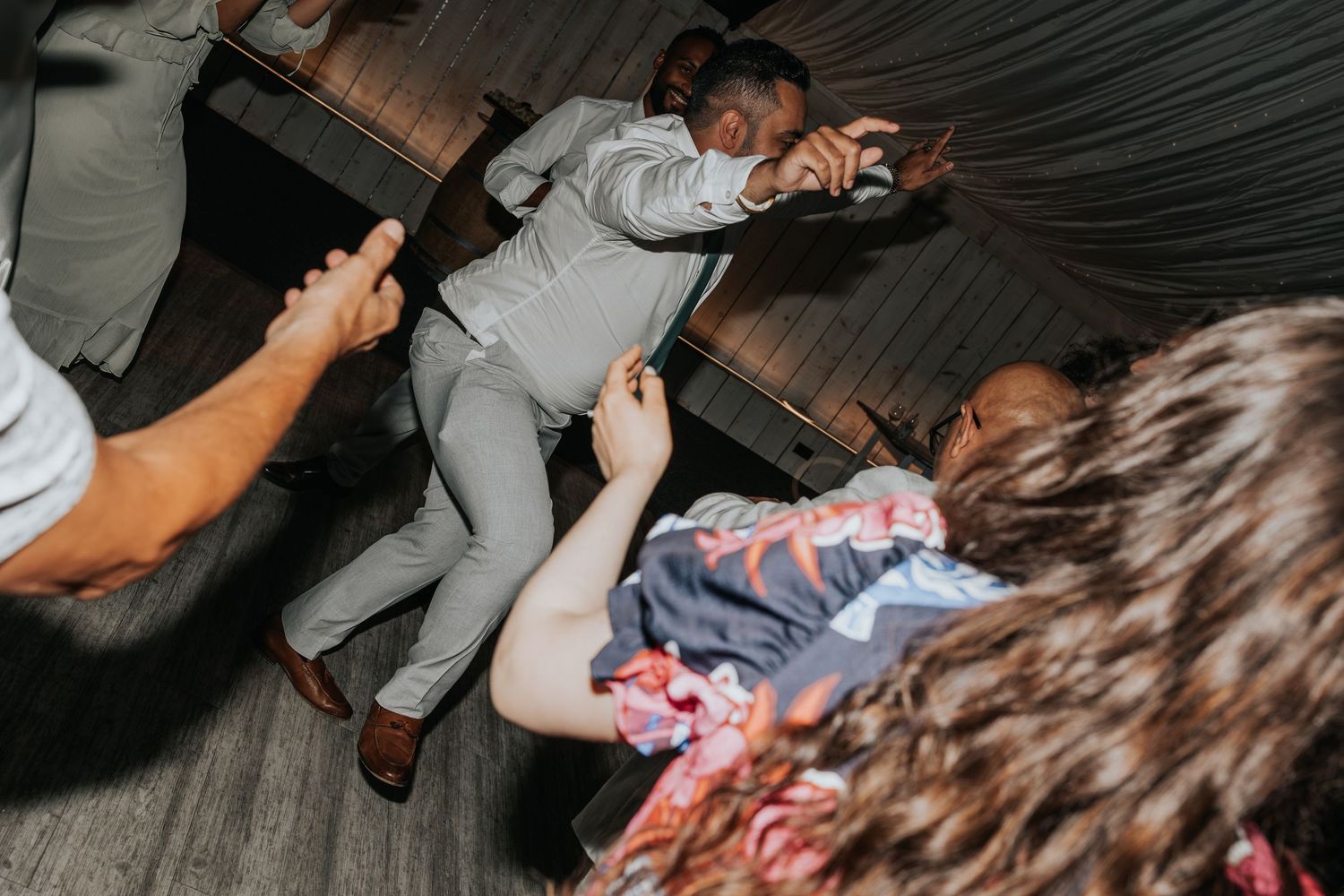 Guests dancing energetically on the dance floor at a lively wedding reception celebration.